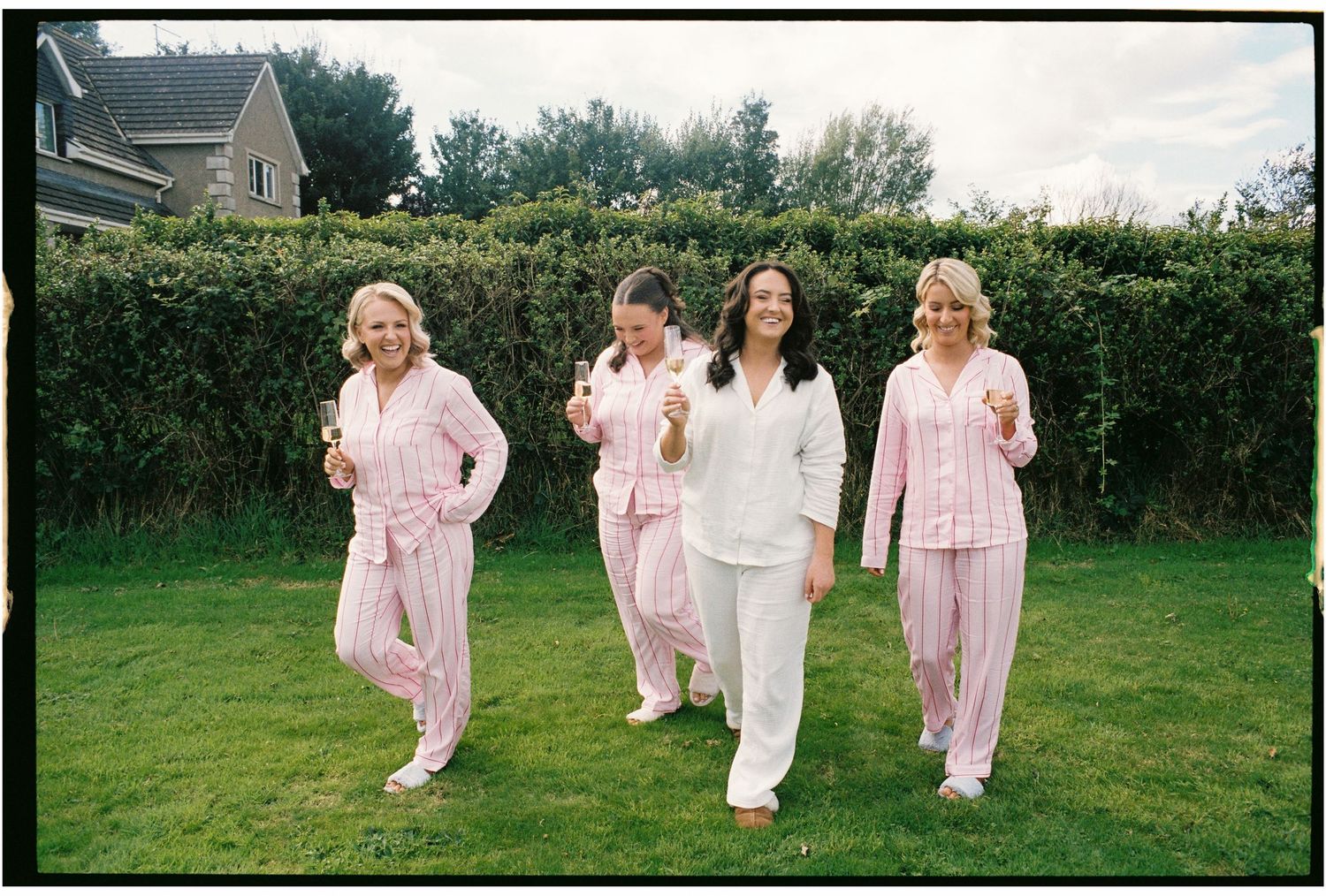 Group wearing matching pink and white outfits walking together in a grassy outdoor setting.