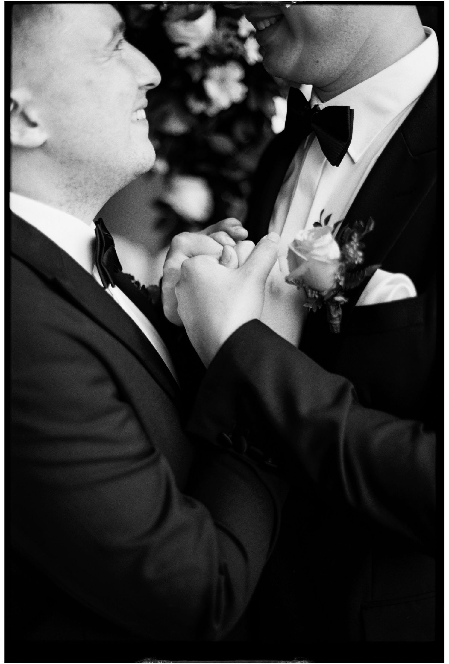 Black and white artistic close-up of two people in formal attire sharing an intimate moment.