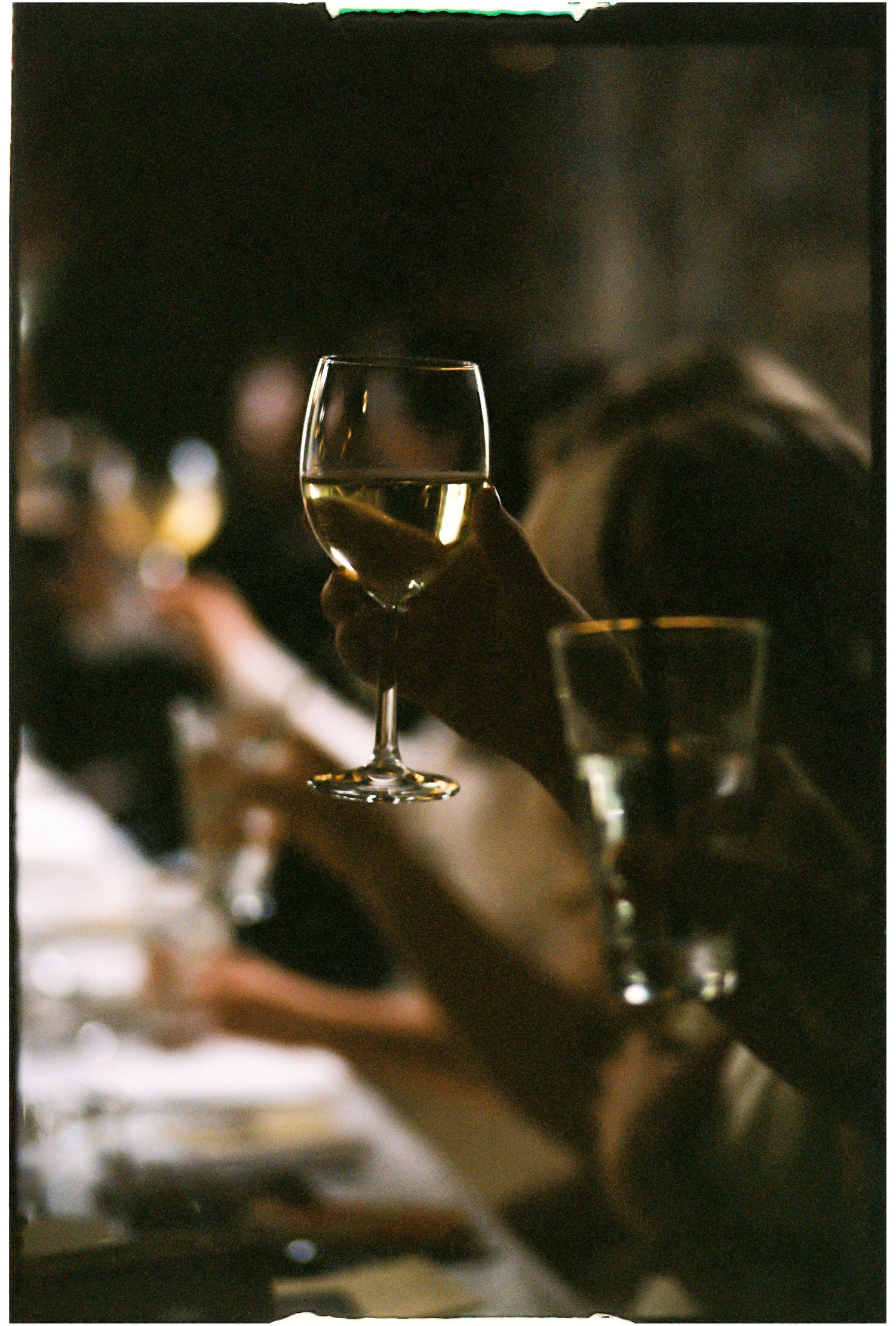 Wine glasses glimmer in dim lighting at an elegant evening event.