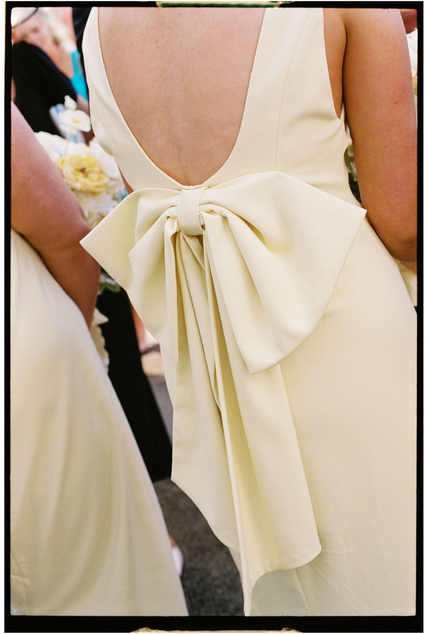 Close-up details of cream-colored bridesmaid dresses with elegant bow accents on the back.