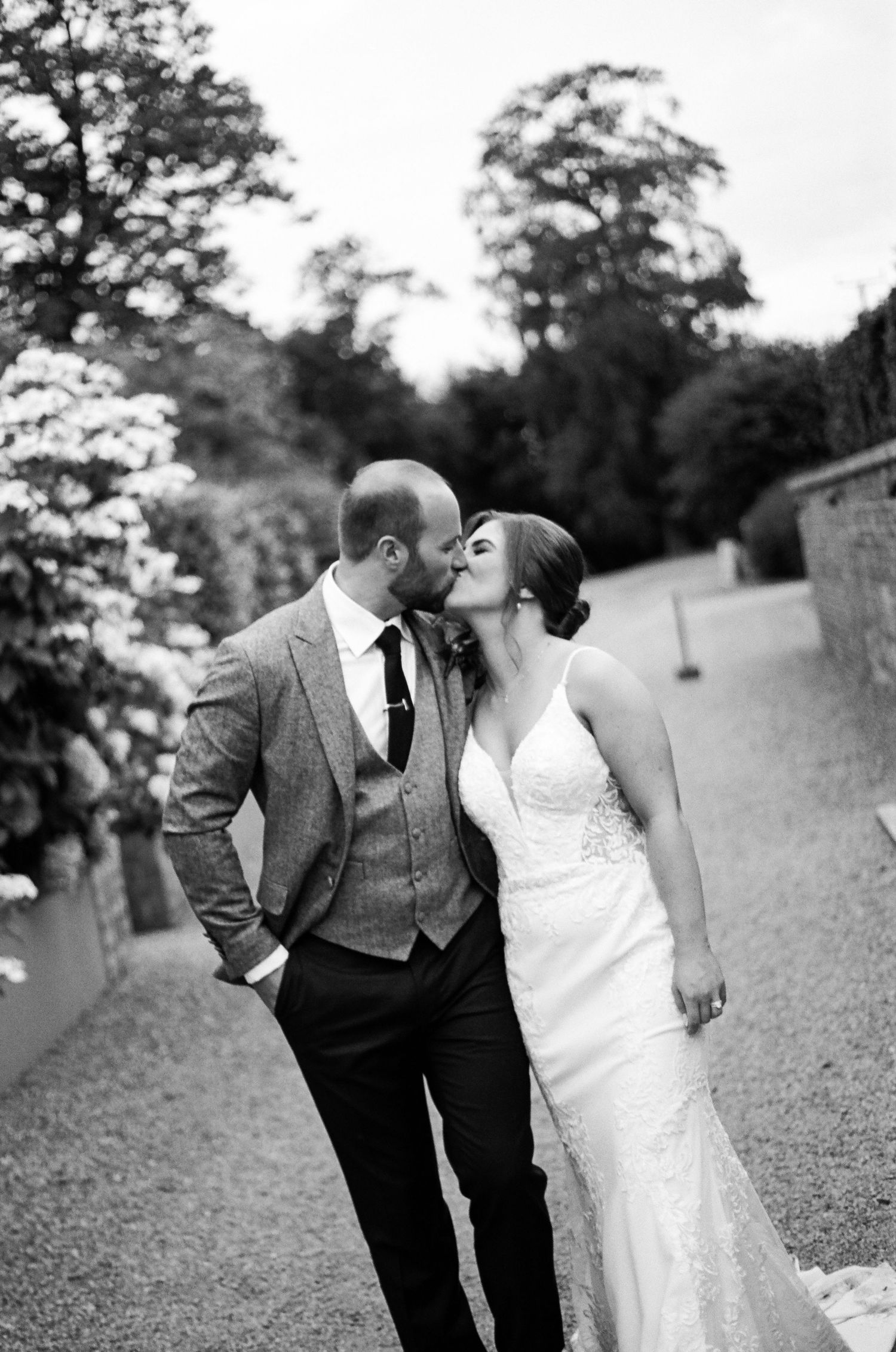 A romantic black and white wedding photo sequence showing a couple sharing tender moments on a garden path.