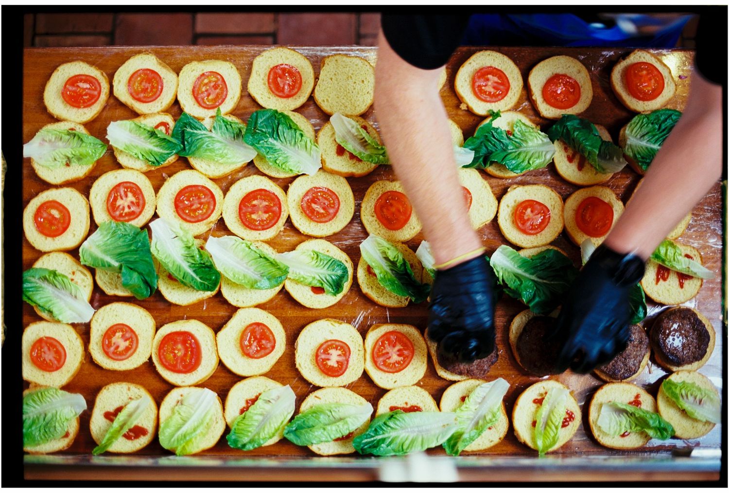Colorful cupcakes with green frosting and red decorative toppings arranged neatly on a wooden tray.