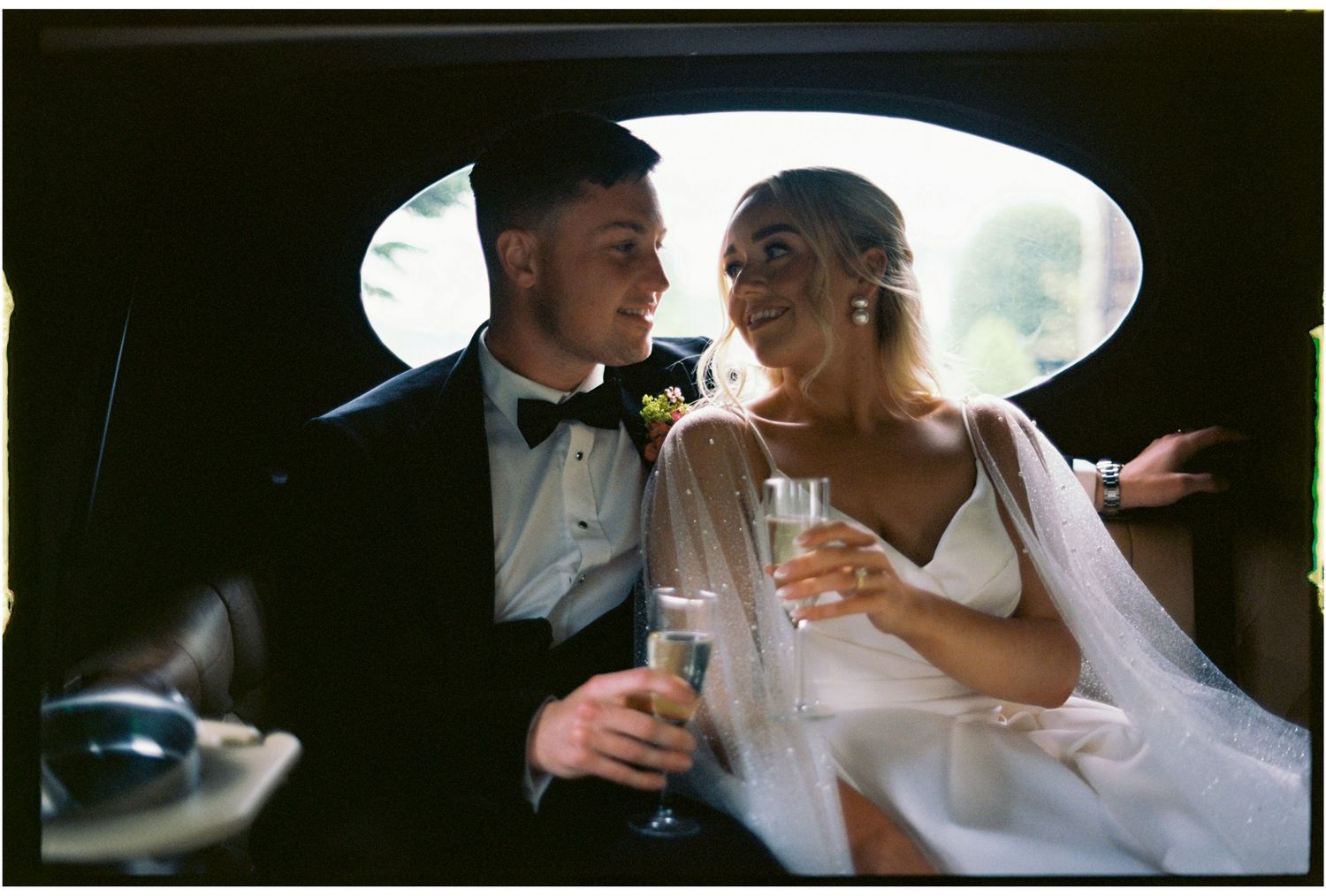 A couple shares an intimate moment while sitting together in formal wedding attire.