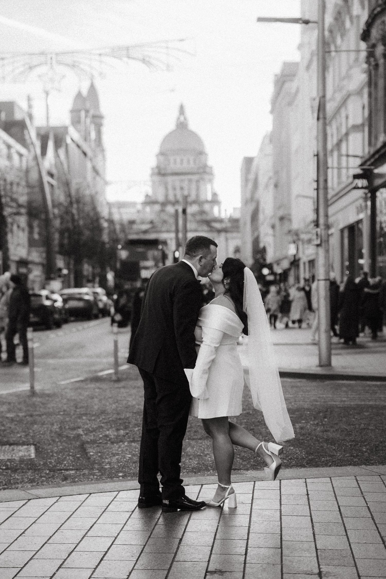 A series of black and white romantic photos showing a couple embracing on a city street with a church in the background.