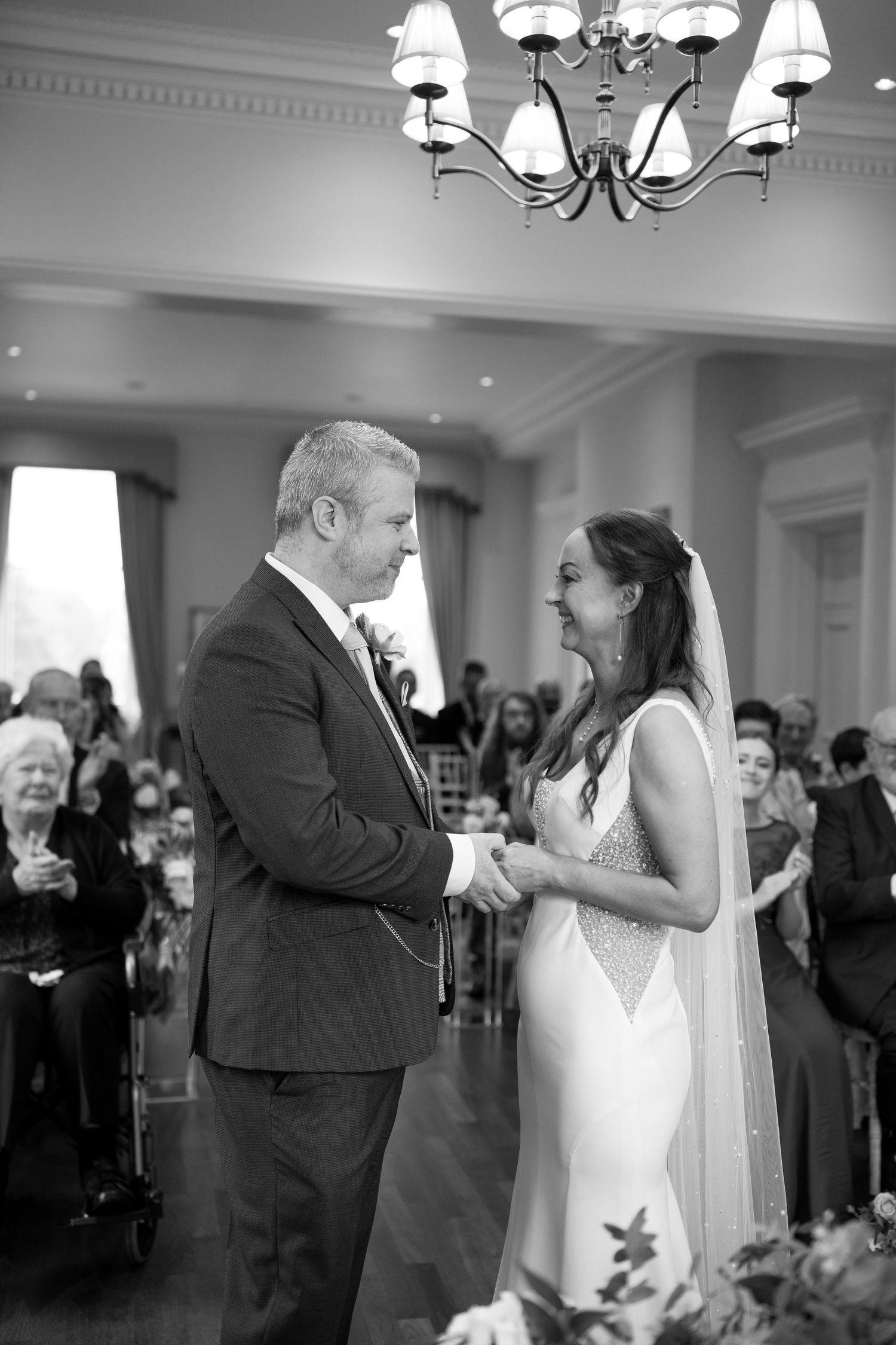 Intimate wedding ceremony moment in an elegant room with chandelier lighting.