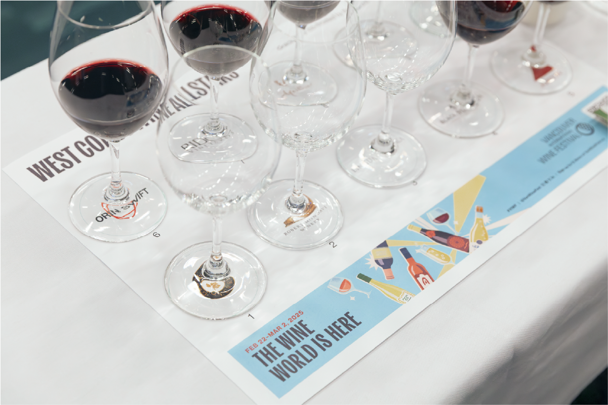 Row of red wine glasses on a white tablecloth at a wine seminar.