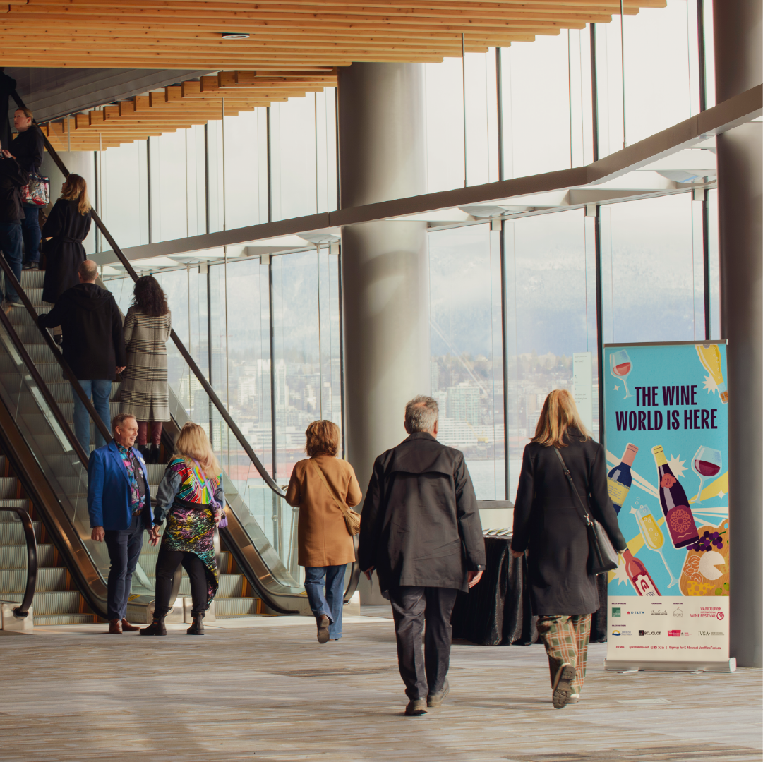 Attendees walking into the Convention Centre past a colorful Vancouver International Wine Festival banner.