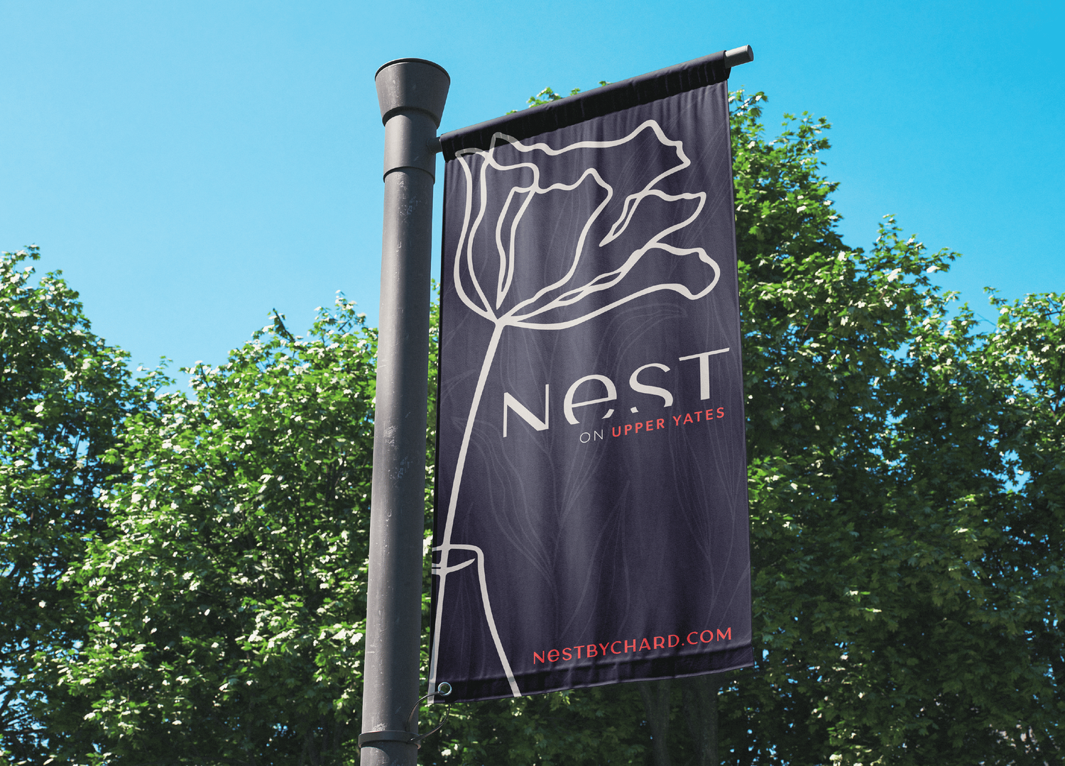 Dark banner on lamp post featuring Nest condominium branding with elegant tulip line art design.