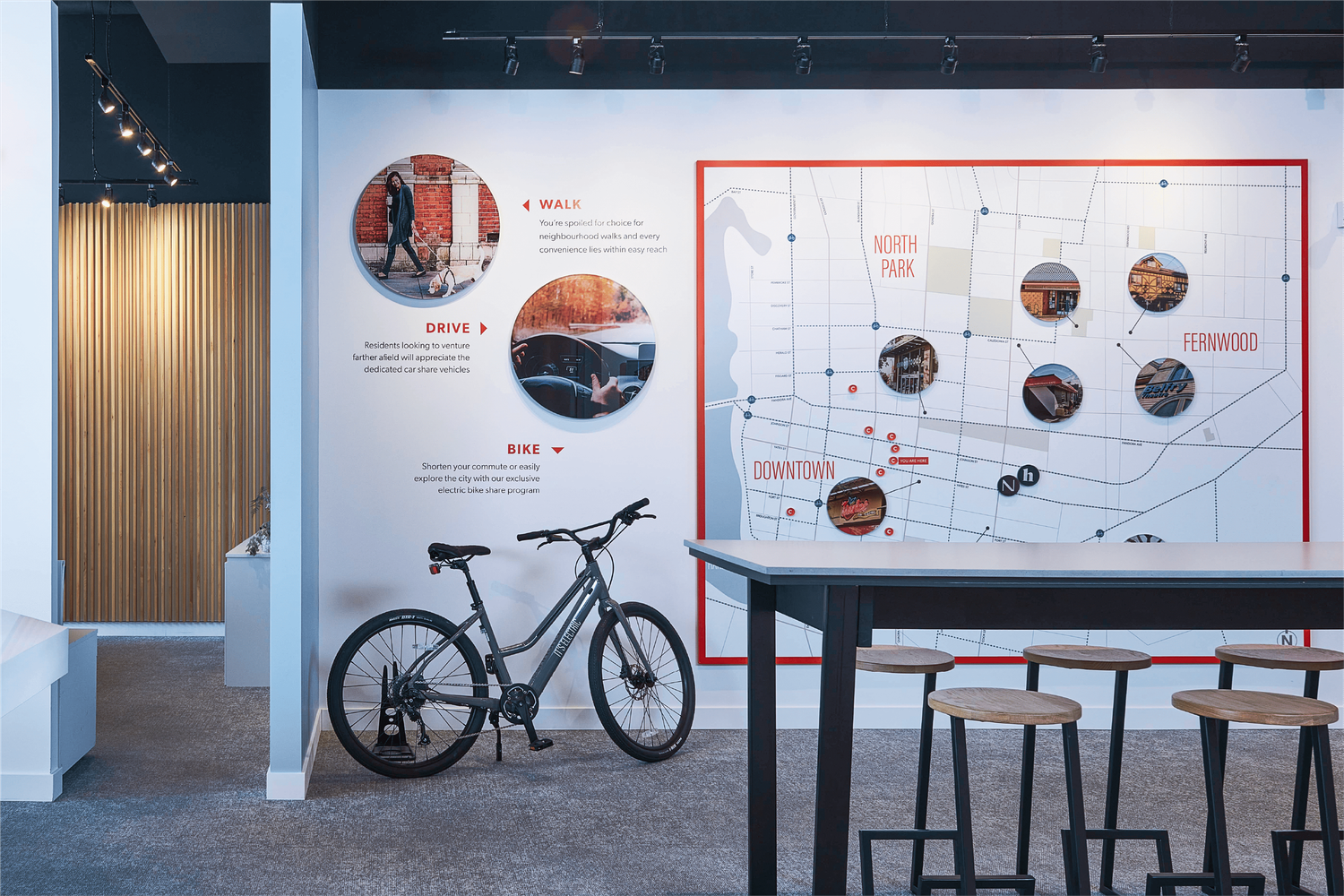 Nest on Upper Yates real estate sales center interior with neighborhood map wall display, bicycle, and bar seating area.