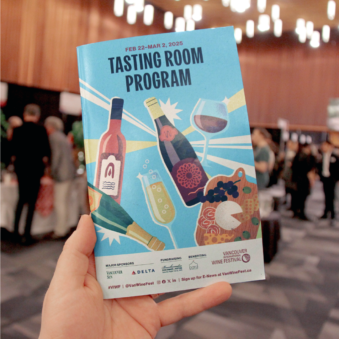 Hand holding a colorful Tasting Room program in the tasting room at the Vancouver International Wine Festival 2025.