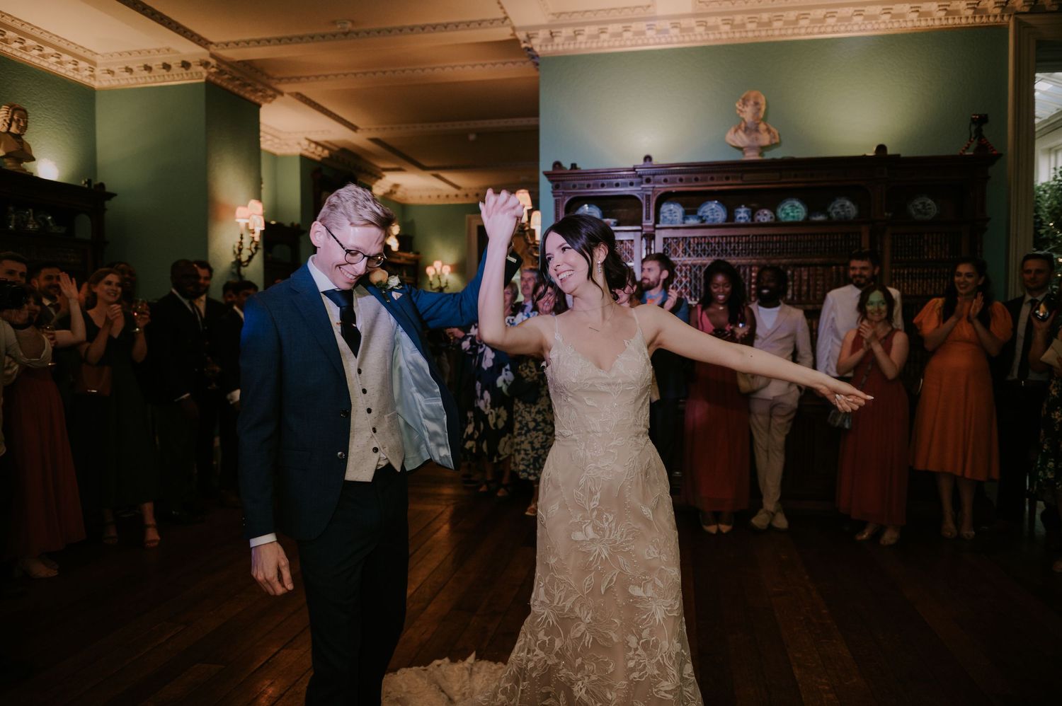 A couple shares a romantic dance with guests surrounding them on the dance floor at a wedding reception.