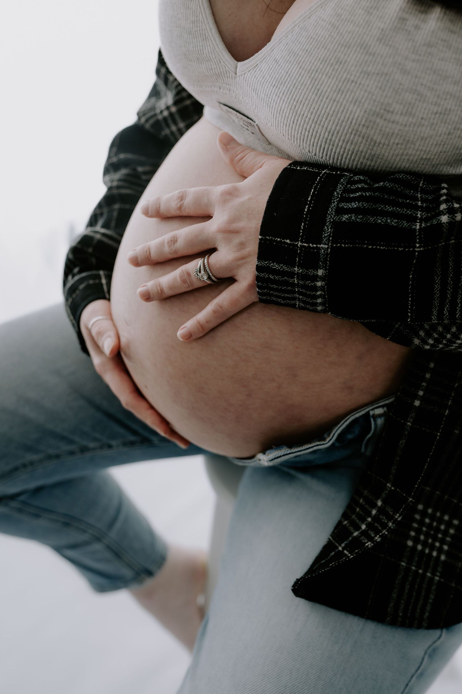 Hands gently cradling pregnant belly, cozy gray sweater, studio, Melton Mowbray.