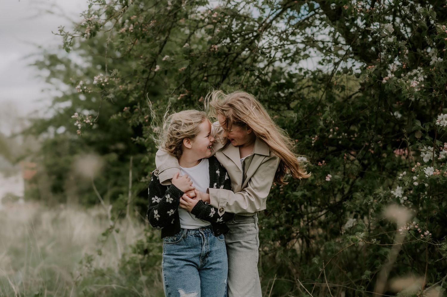 Romantic couple embraces in a dreamy outdoor setting with soft natural lighting and greenery in the background.