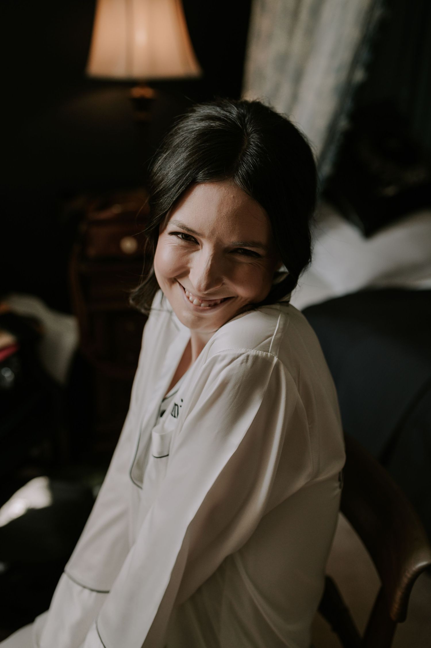 A series of four moody images showing someone in a white sweater with dark hair in a low light setting smiling playfully.