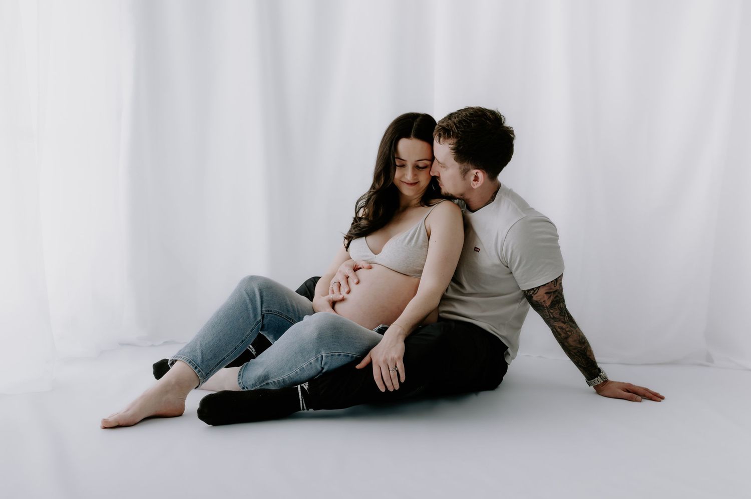 Romantic couple in casual clothing embracing on floor, pregnant woman, studio maternity, Melton Mowbray.