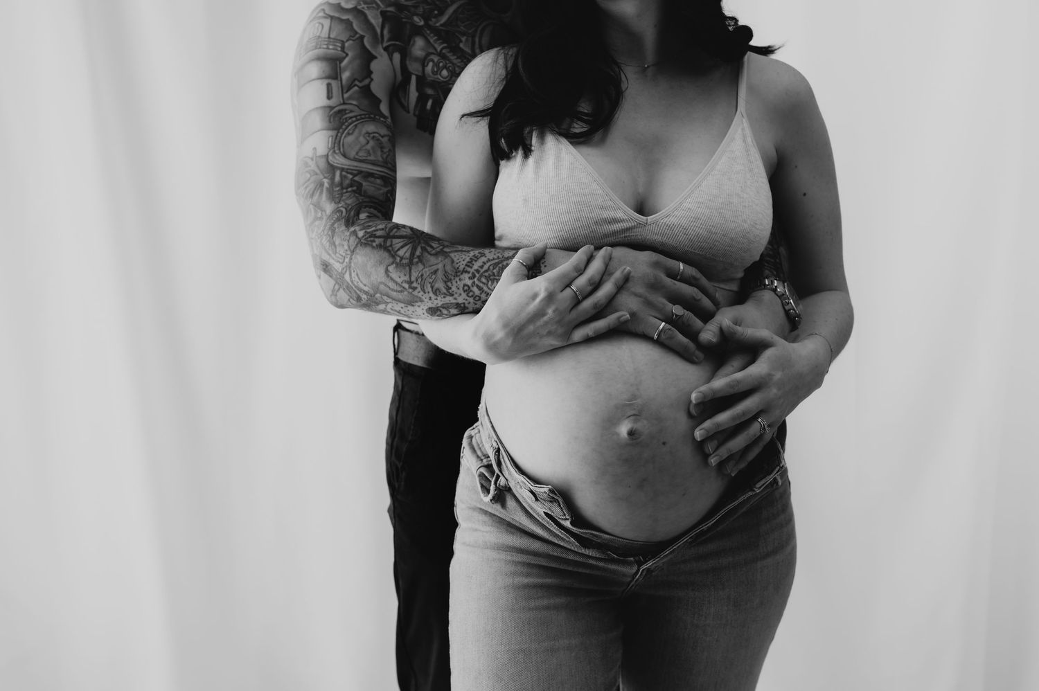 Black and white maternity photo, pregnant belly embraced by tattooed arms, studio, Melton Mowbray.