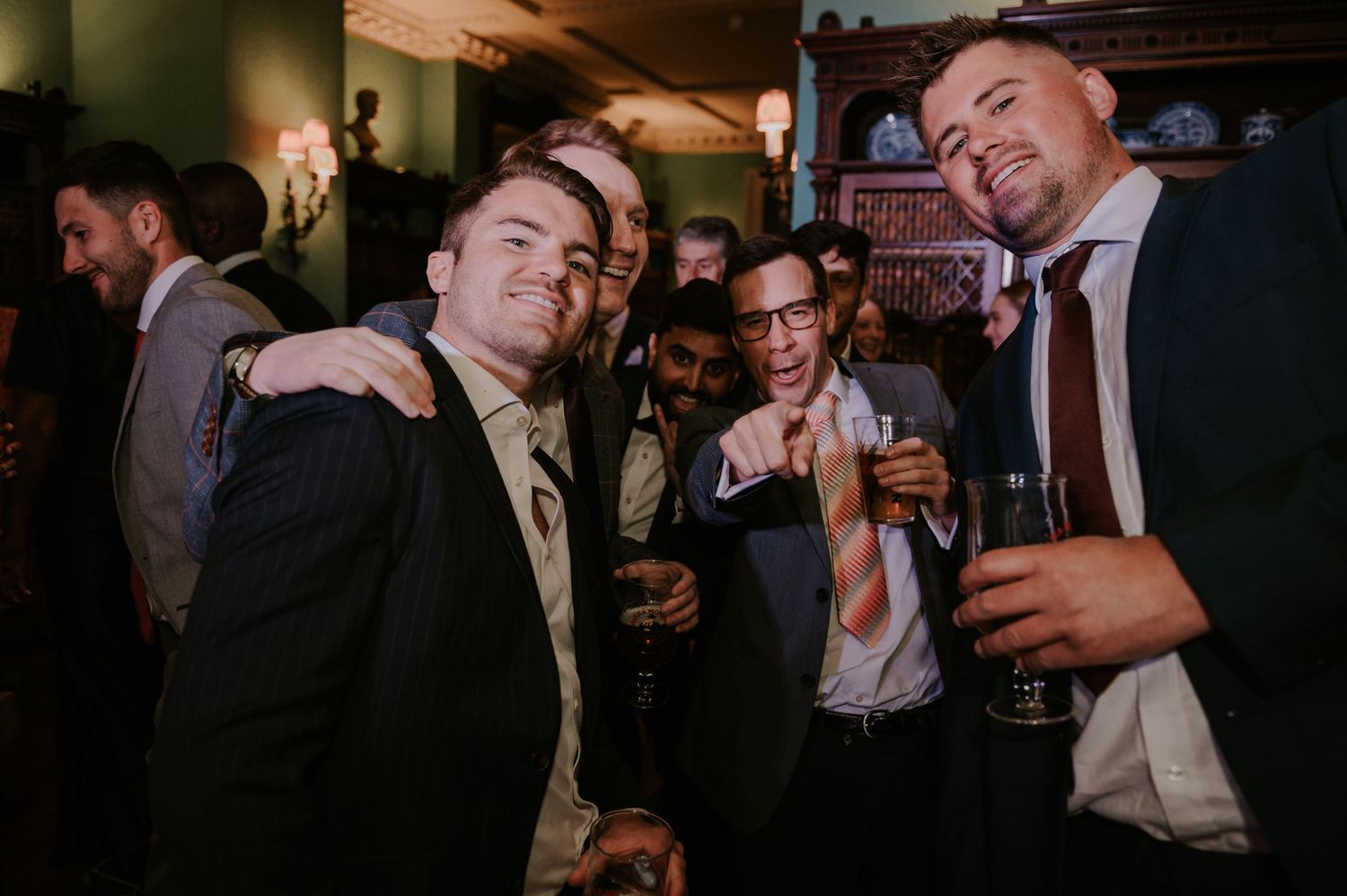 A group of formally dressed party guests enjoying drinks and celebrating together at an evening event.