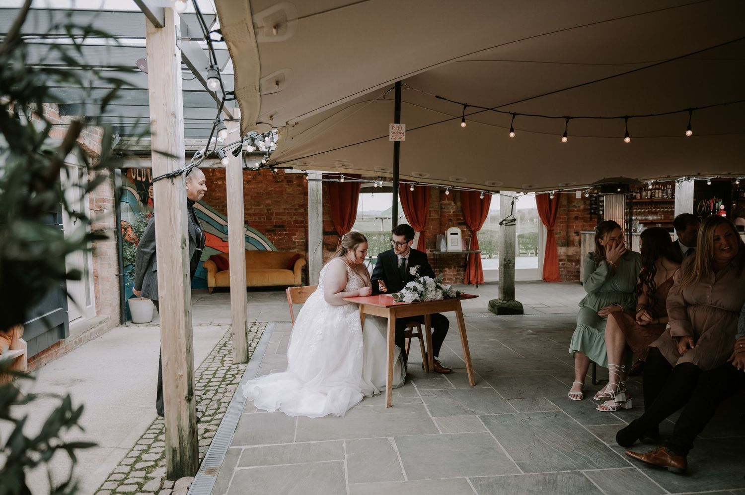 Couple signing register in rustic old cow shed, wedding venue, Melton Mowbray