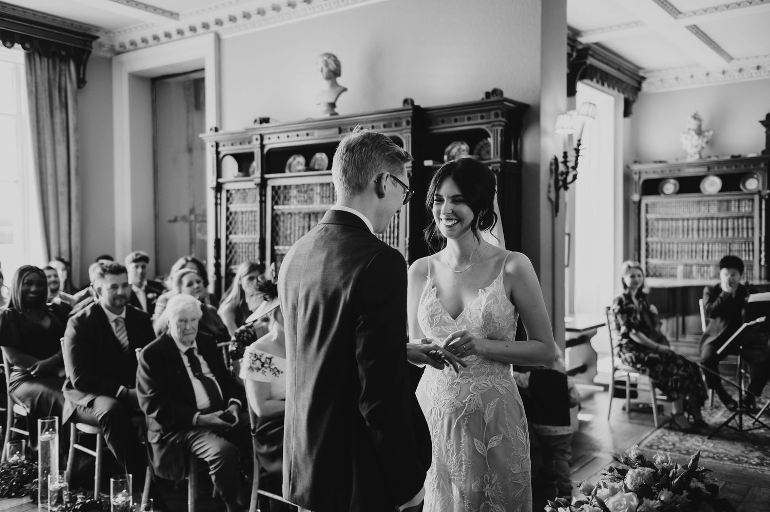 Wedding party mingles in an elegant reception hall decorated with traditional white decor and ornate details.