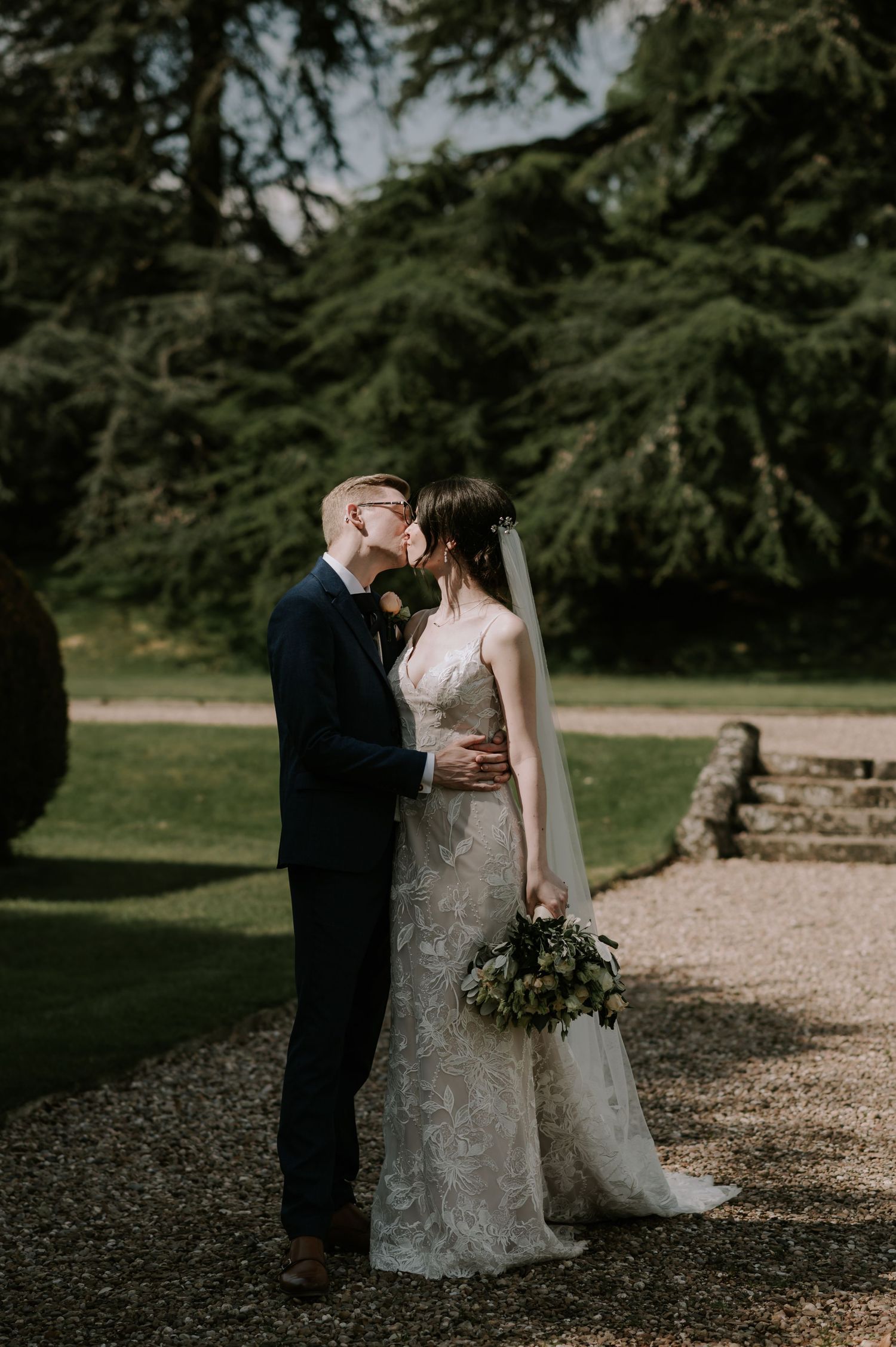 Romantic artistic wedding portraits feature a couple embracing outdoors in a beautifully landscaped garden setting.