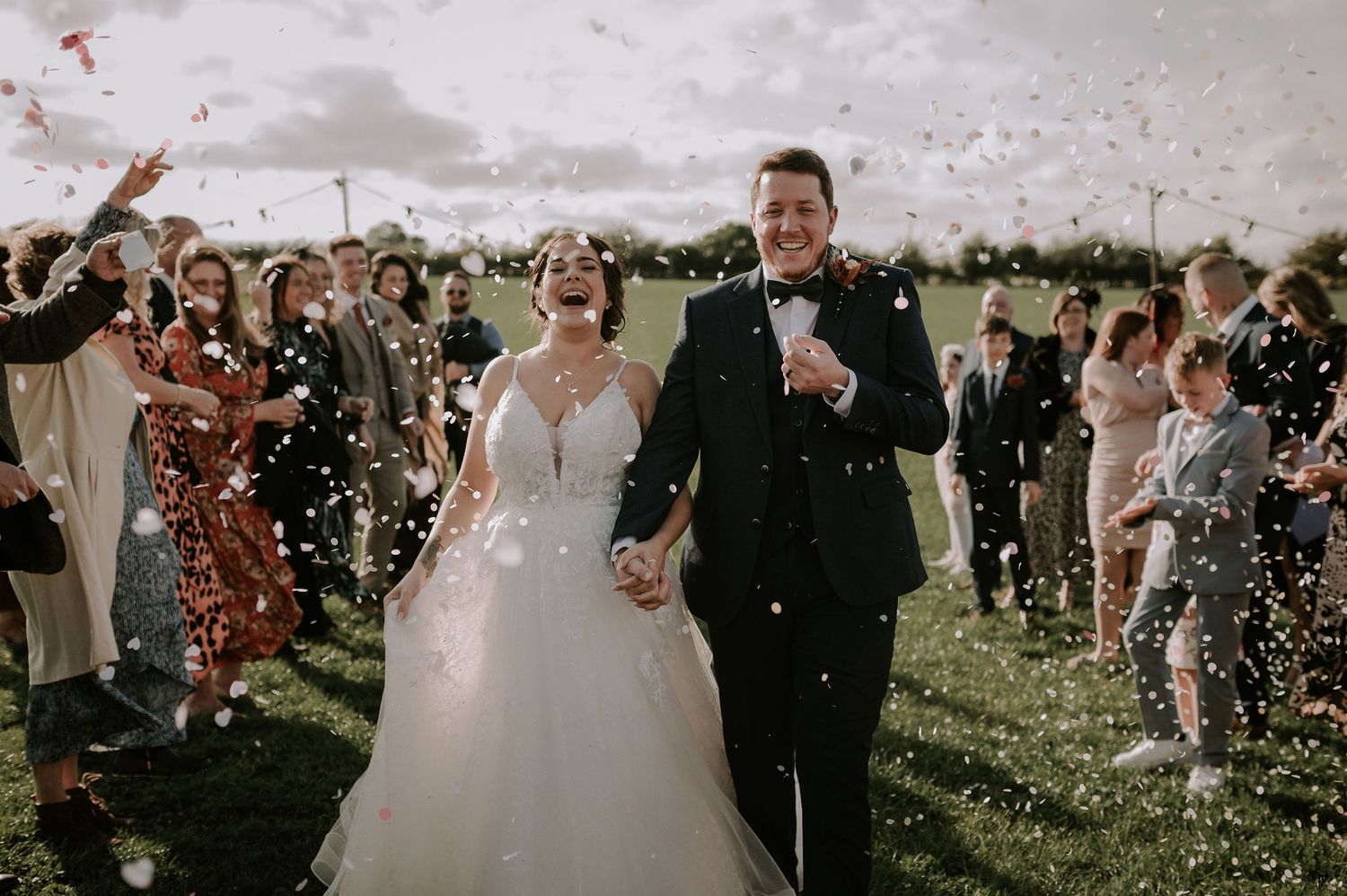 Wedding celebration with confetti being thrown over the couple in a sunny outdoor setting. Melton Mowbray wedding