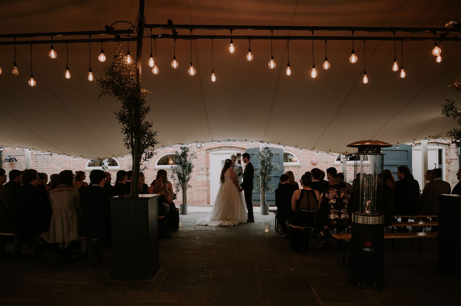 String lights illuminate outdoor wedding reception tent during a wedding ceremony, old cow shed, melton mowbray.