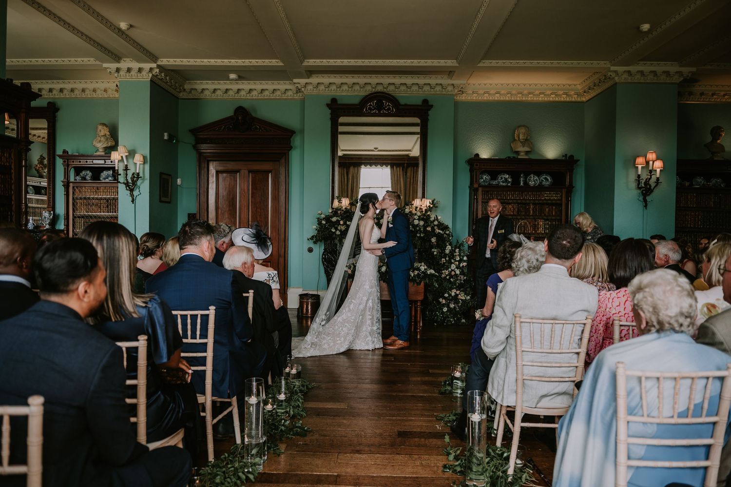 Wedding ceremony taking place in elegant vintage room with mint green walls and ornate molding at historic venue.