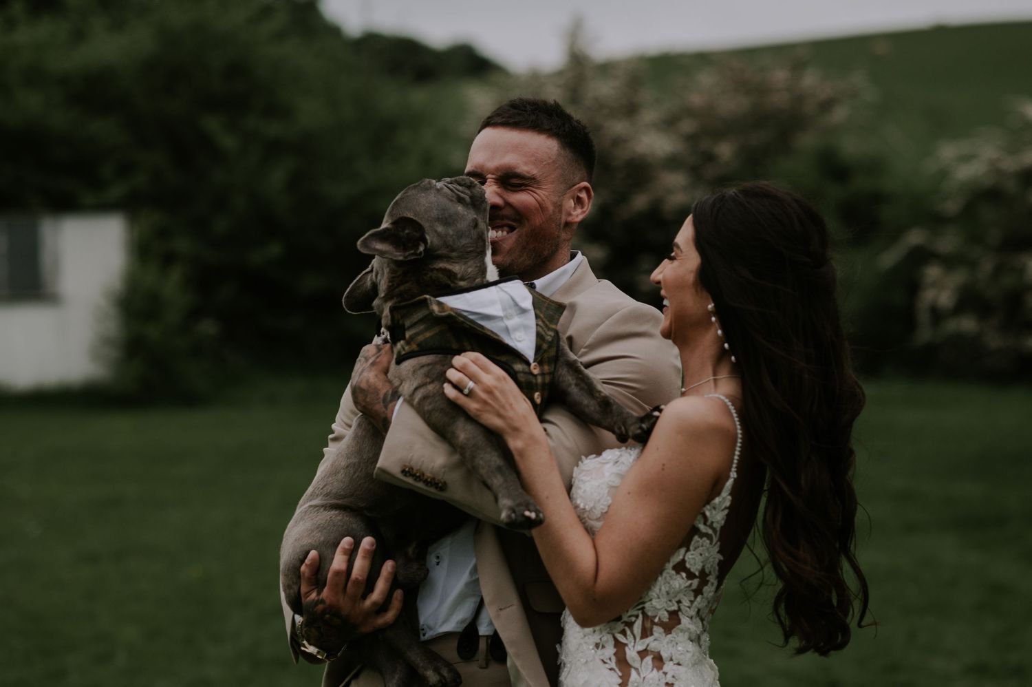 Couple holding their pug dog smiling in green field, Melton Mowbray family photography