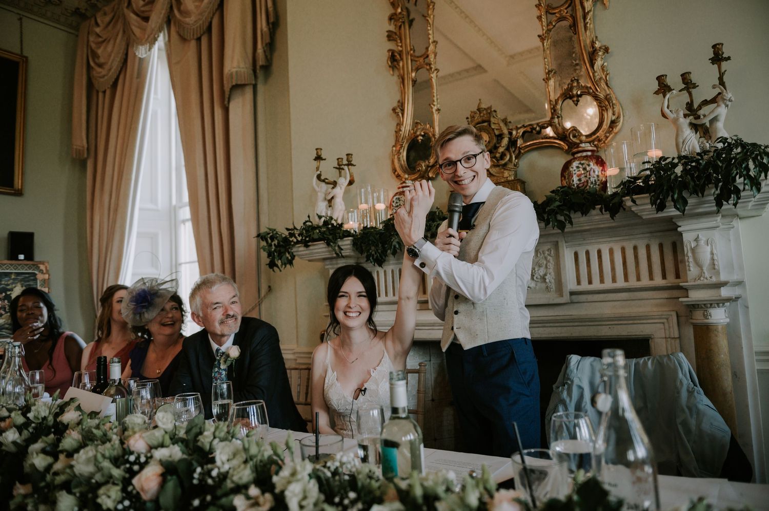 Wedding reception guests enjoy champagne toasts in an elegant ballroom with ornate decor and chandeliers.