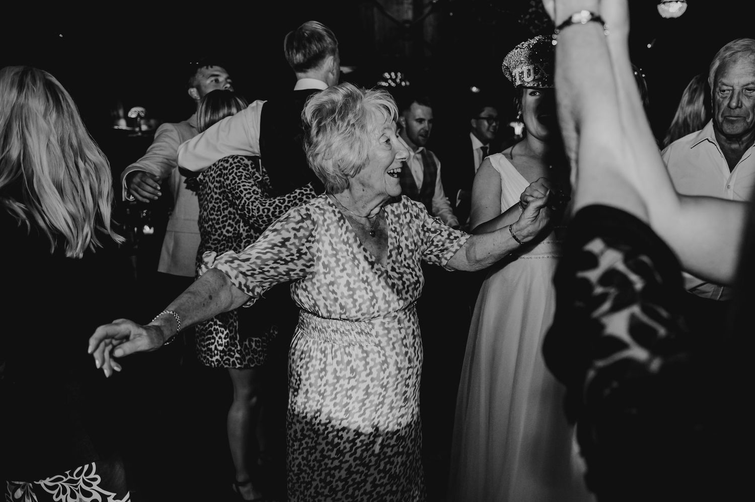 A person in a sparkly dress dances joyfully at a lively black and white party celebration.