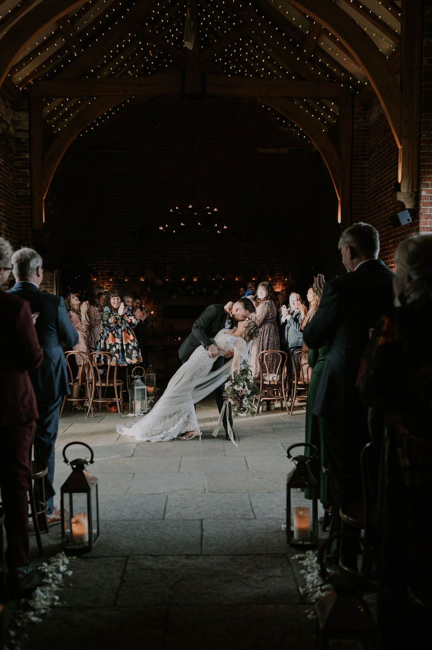 Couple exiting ceremony halfway down aisle, dip kiss, guests cheering, Hazel gap barn, Derby wedding
