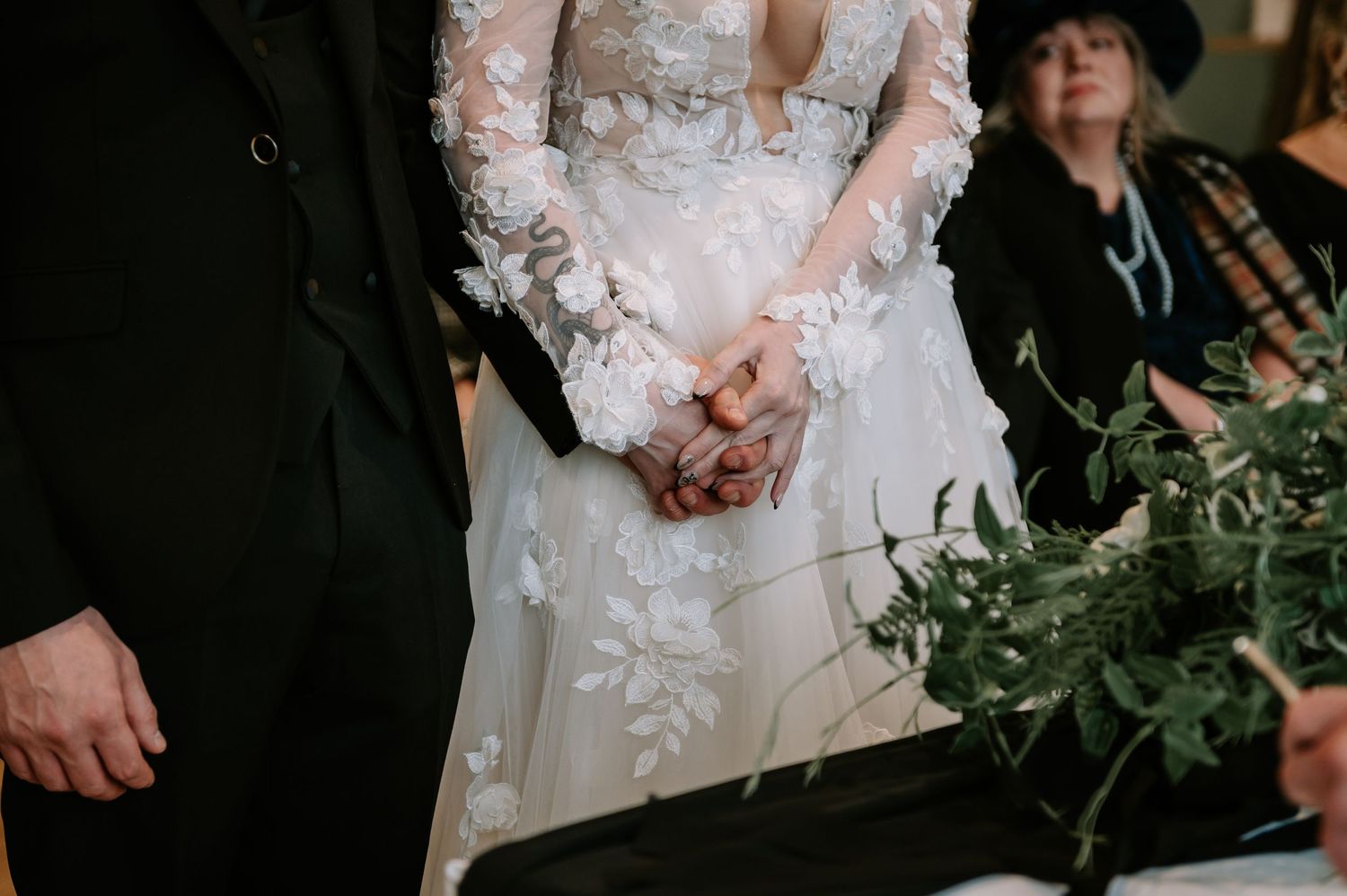 Close-up detail of a wedding dress with delicate lace sleeves and floral appliques during ceremony.