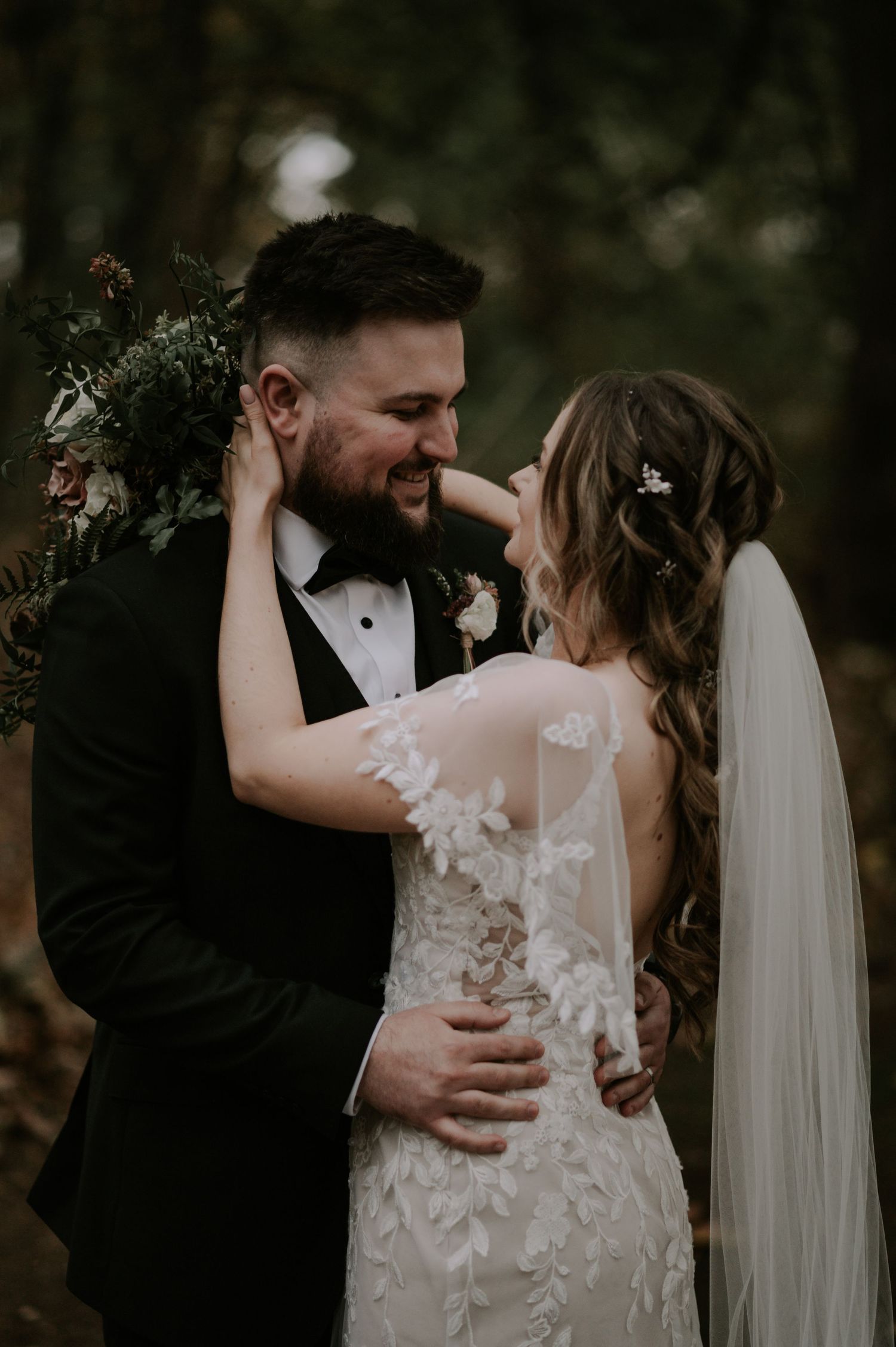 Romantic wedding couple outdoors with moody lighting, bride in lace gown.