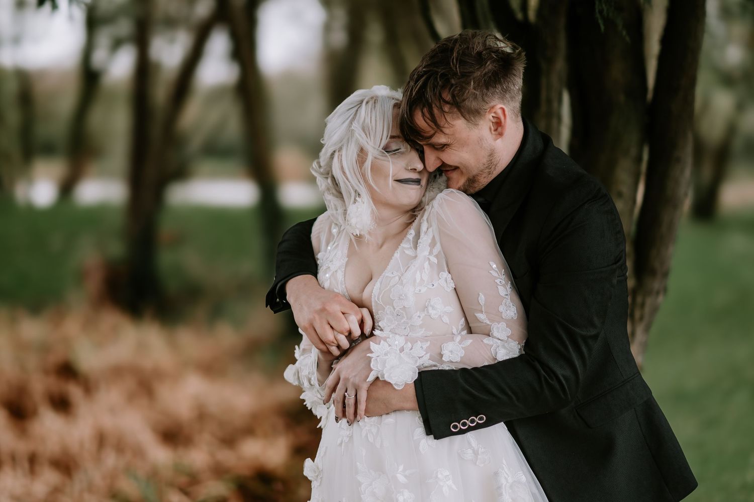Romantic outdoor wedding moment captured in a natural forest setting with autumn leaves.