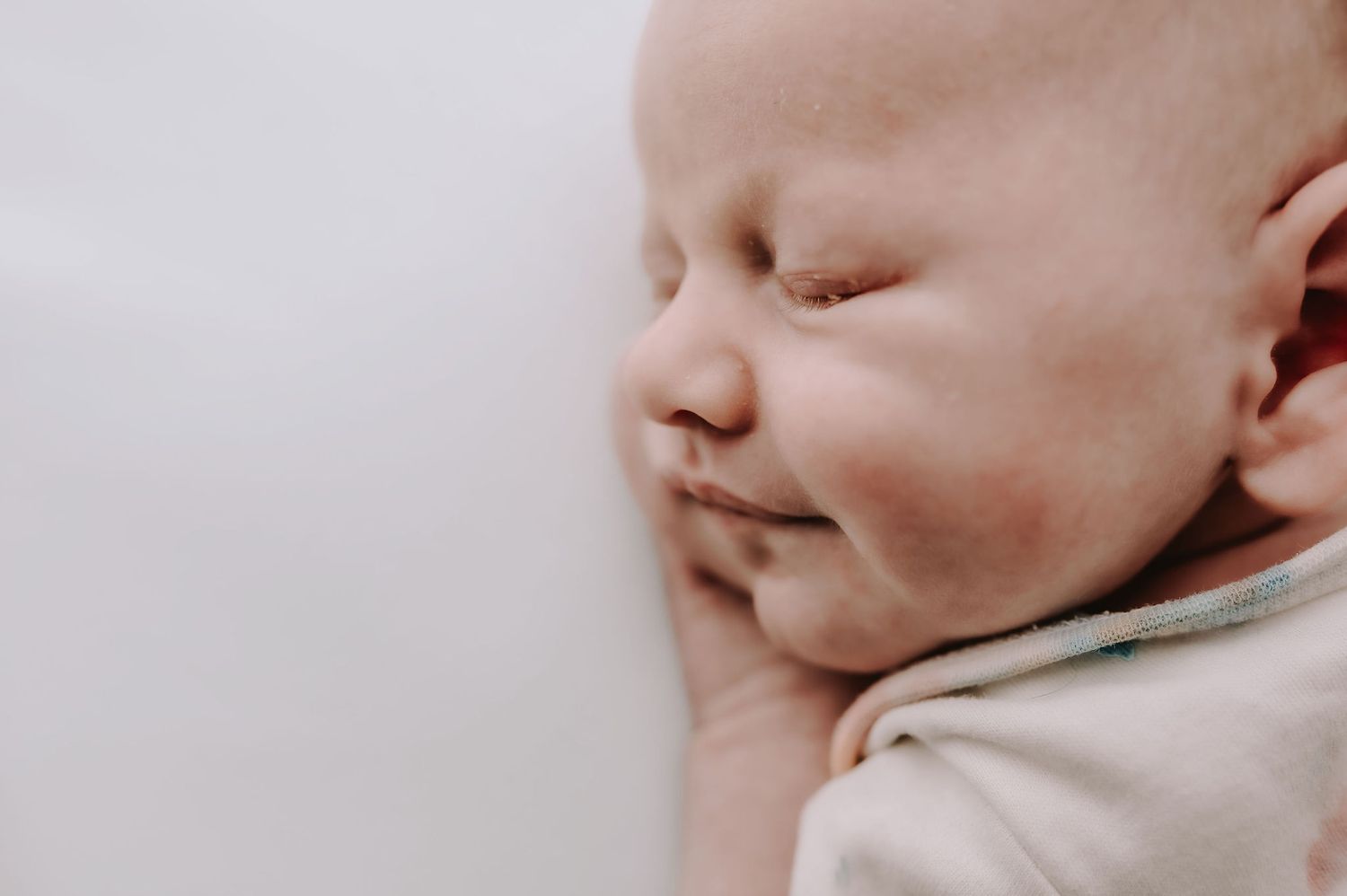 A close up, side profile of a newborn babies face, eyes closed with a slight smile. Newborn photoshoot in Melton Mowbray