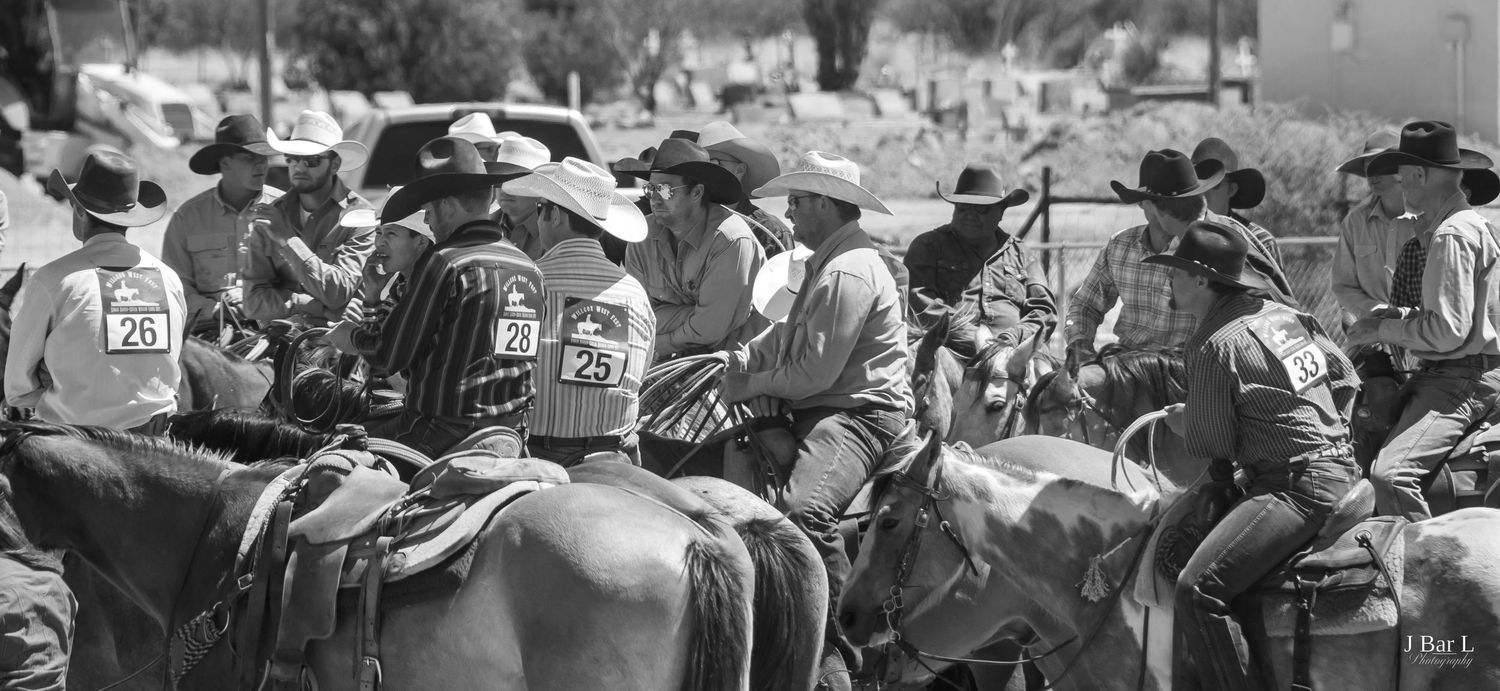Black and white photo of cowboys on horseback gathered together at a rodeo event.