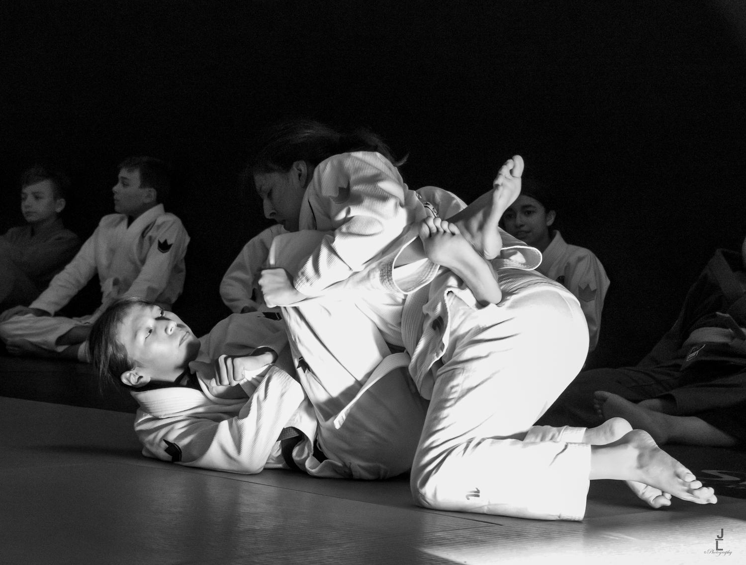 Black and white photo of two judo athletes grappling on the mat during a competition.