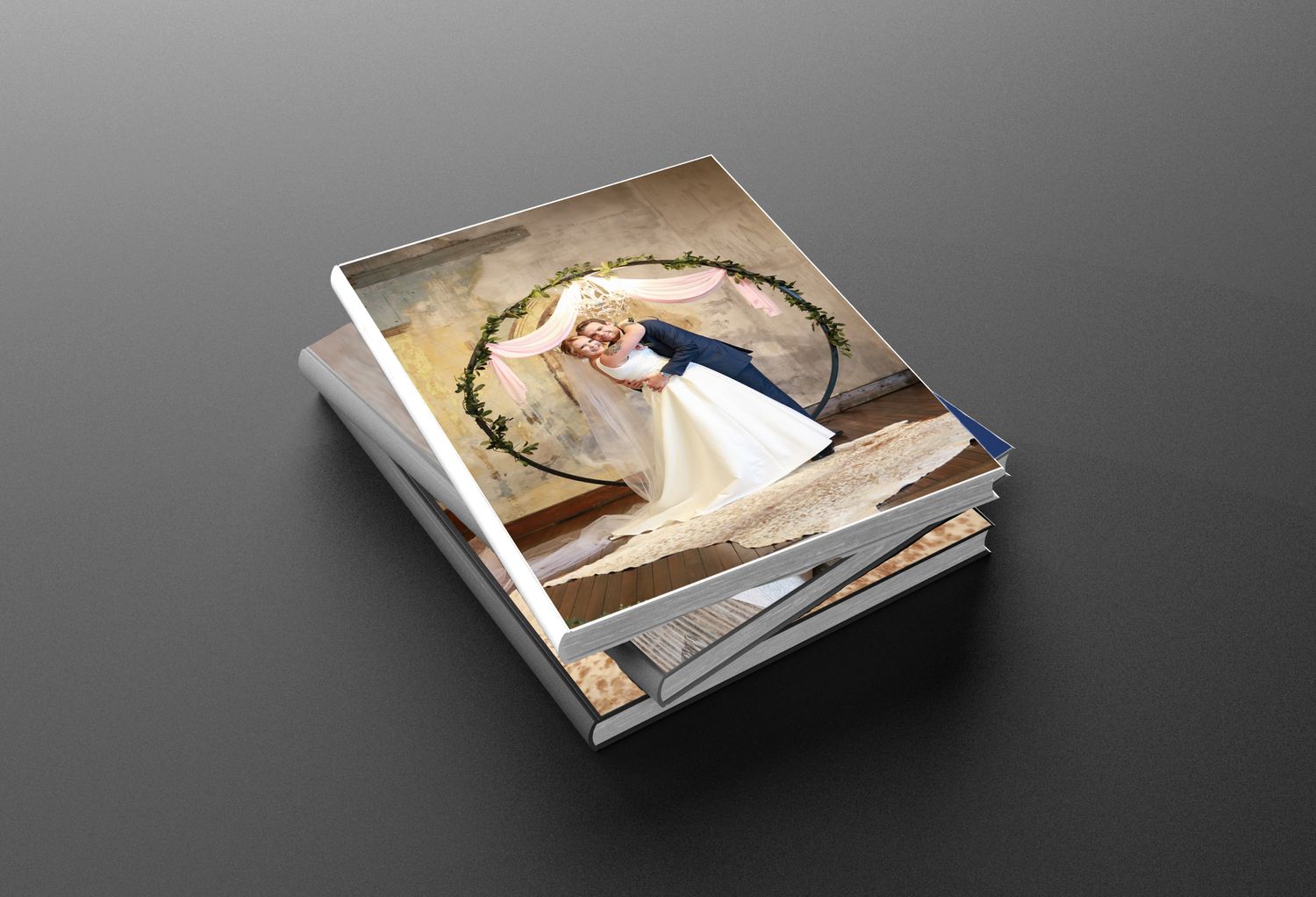 Stack of wedding photo books featuring a bride and groom posing in a floral hoop on the cover.