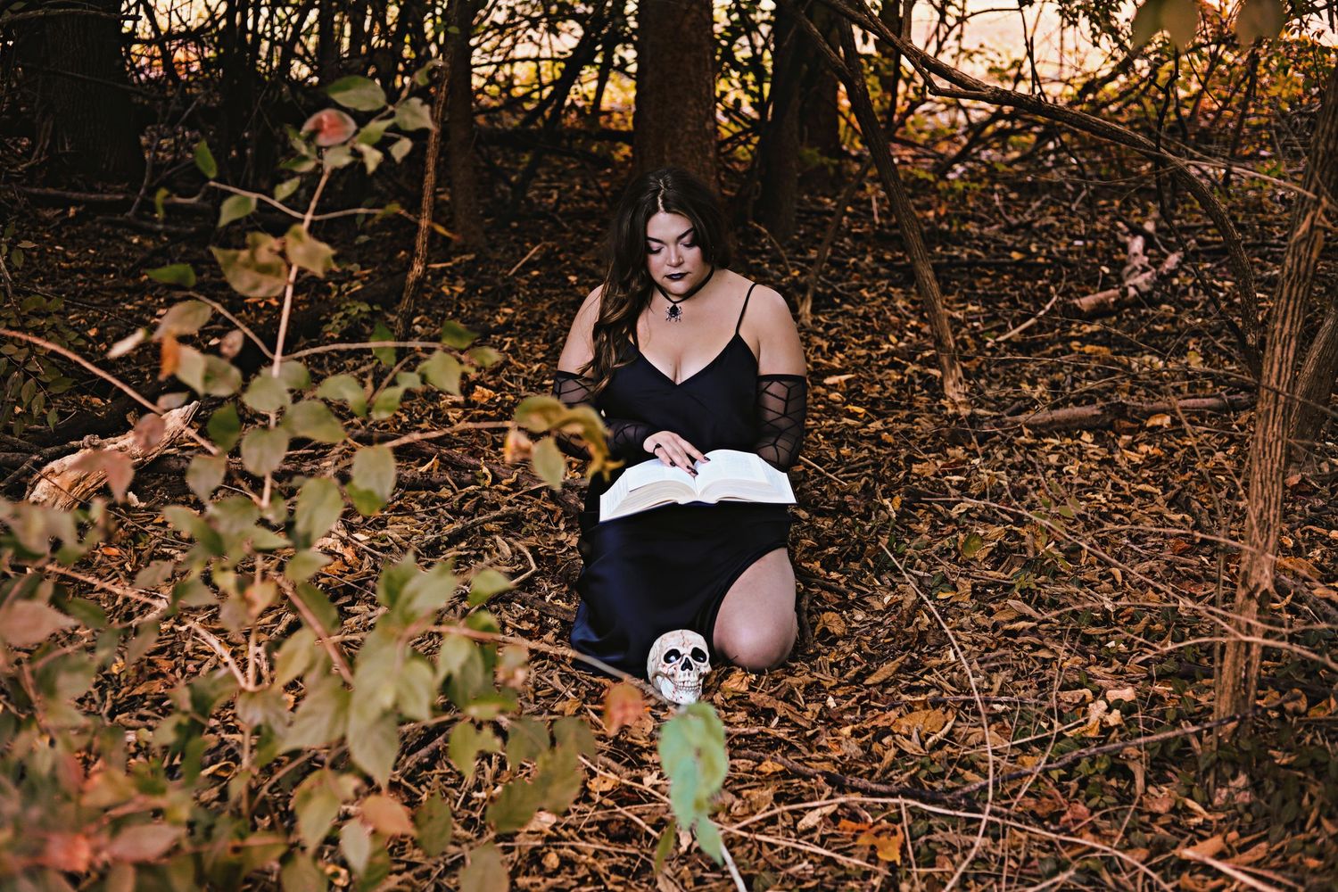 Woman in silk gown reading a spell book in the woods in Greenwood, IN.