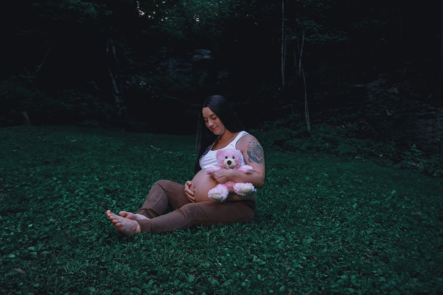 Pregnant mom holding pink teddy bear during maternity session in Bloomington, IN.
