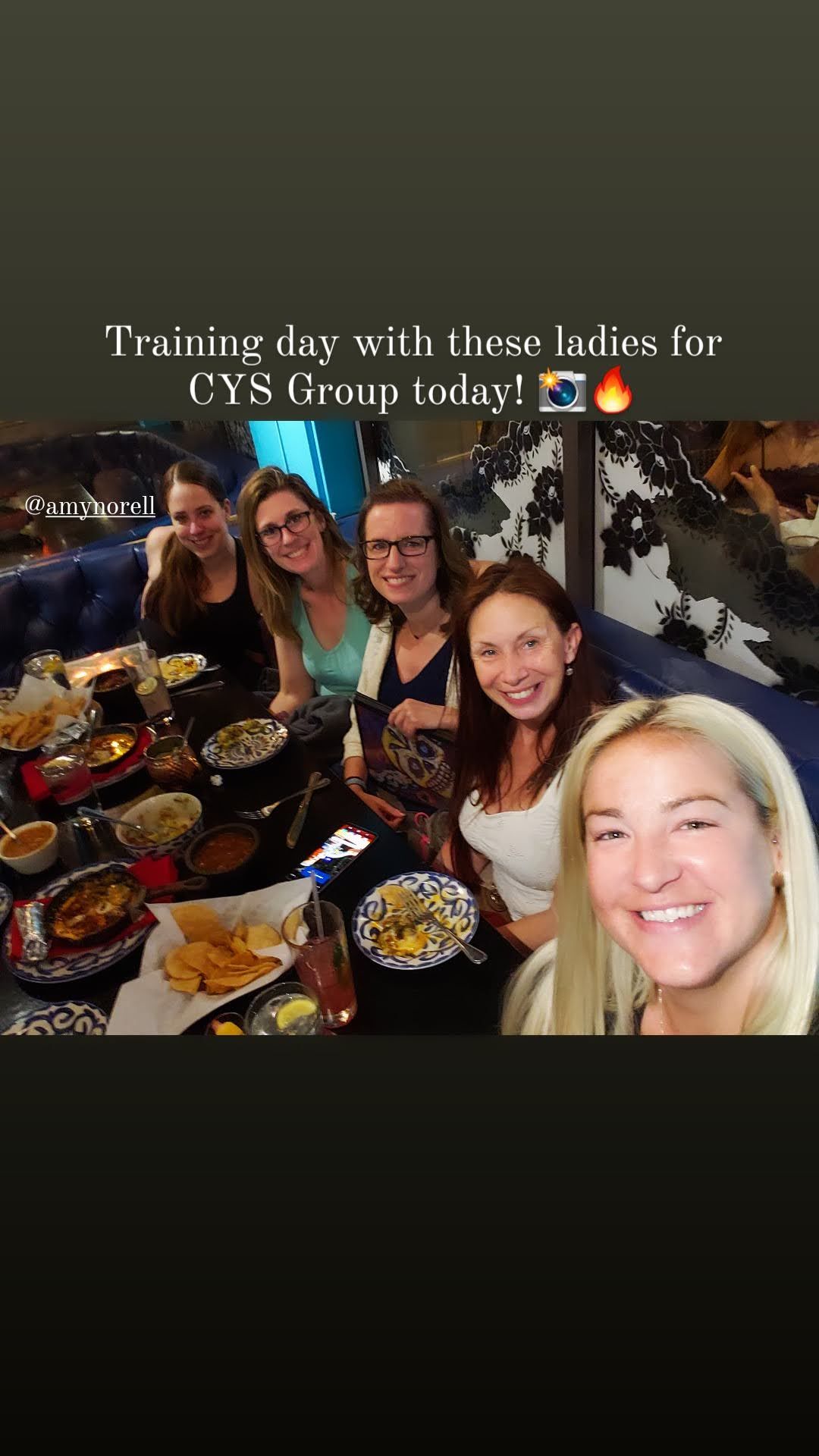 Five women smiling at a restaurant table during a CYS Group training day with food and drinks.