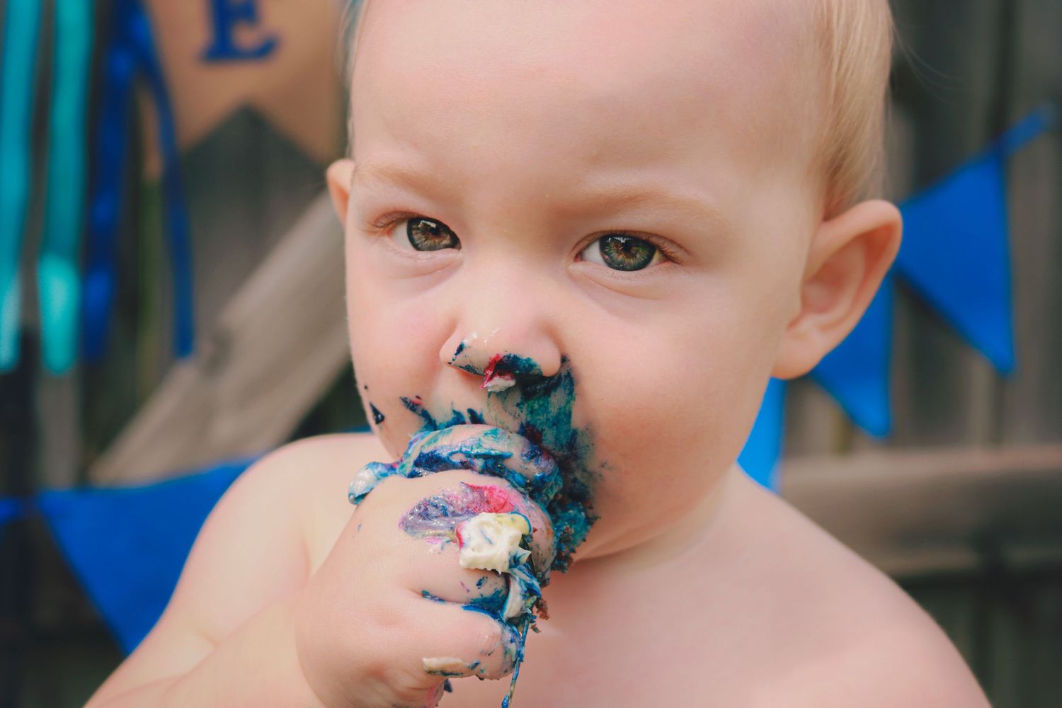 Close up of birthday boy's face covered in cake.