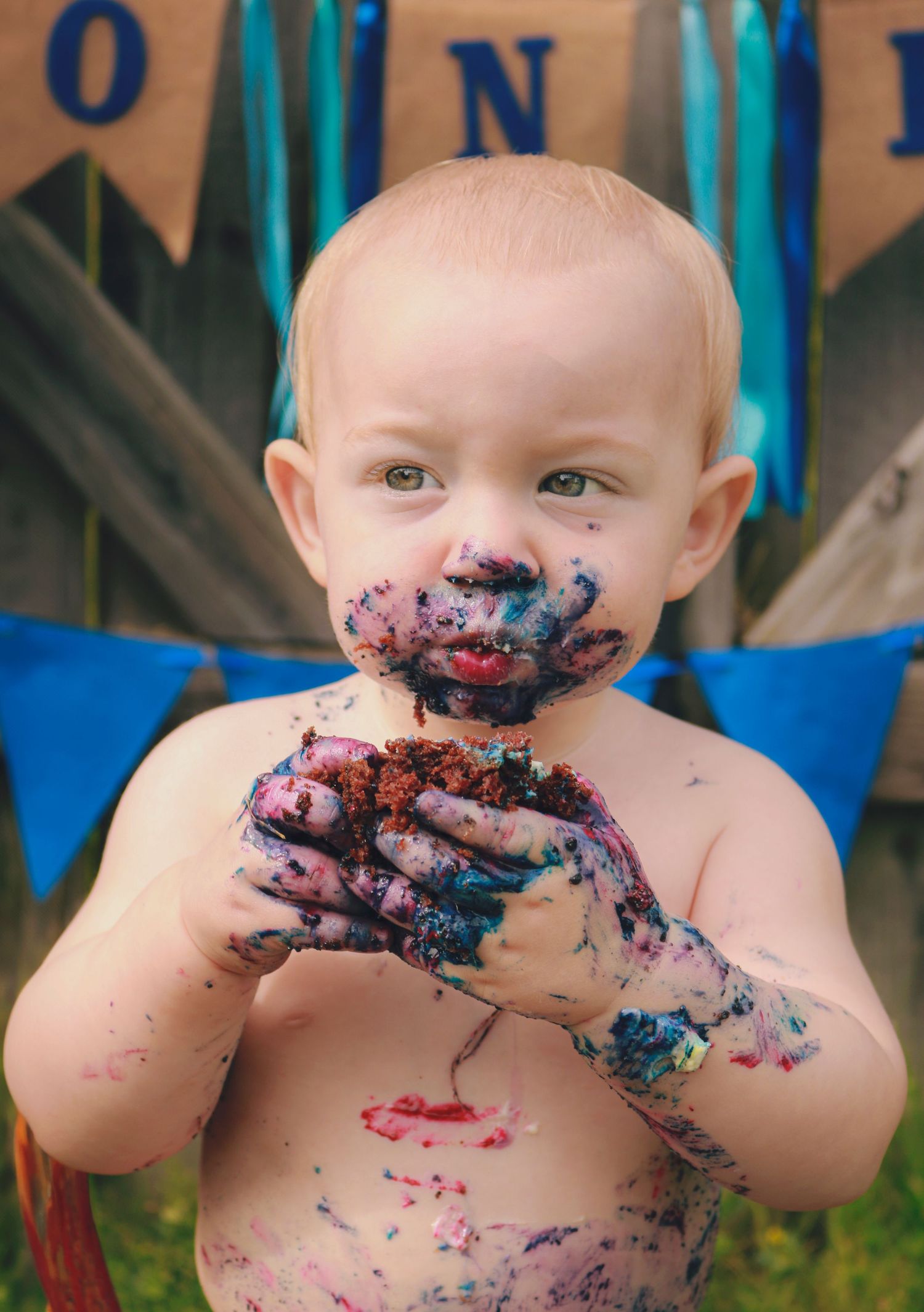 One year old boy eating his cake at a cake smash photoshoot.