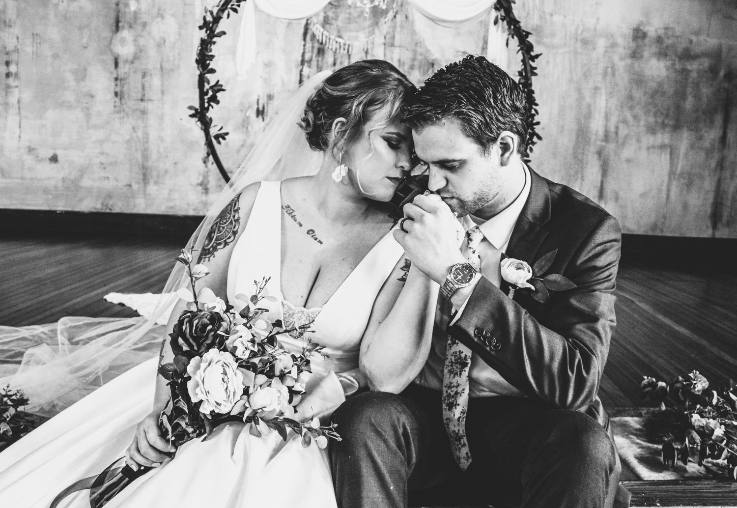Bride and Groom sitting together with groom kissing bride's hand.