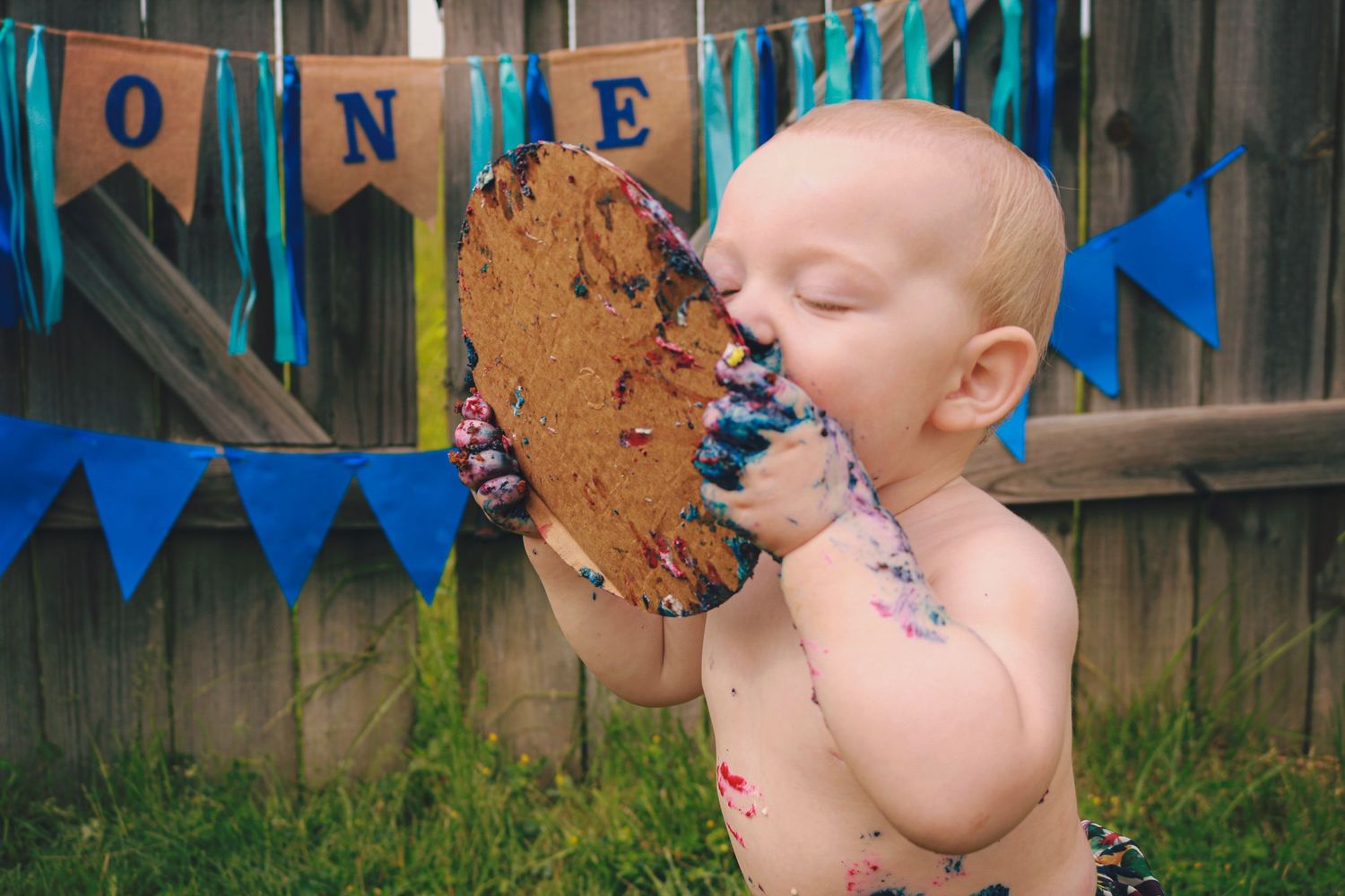 Baby boy licking plate clean from smash cake photoshoot in Greenfield, IN.