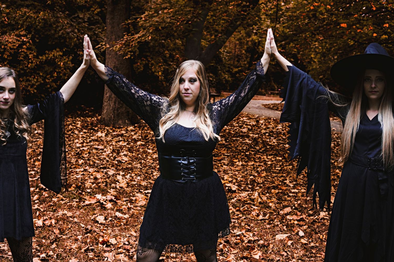 Women with lacy dresses standing hand to hands in the sky creating a spell in the woods.