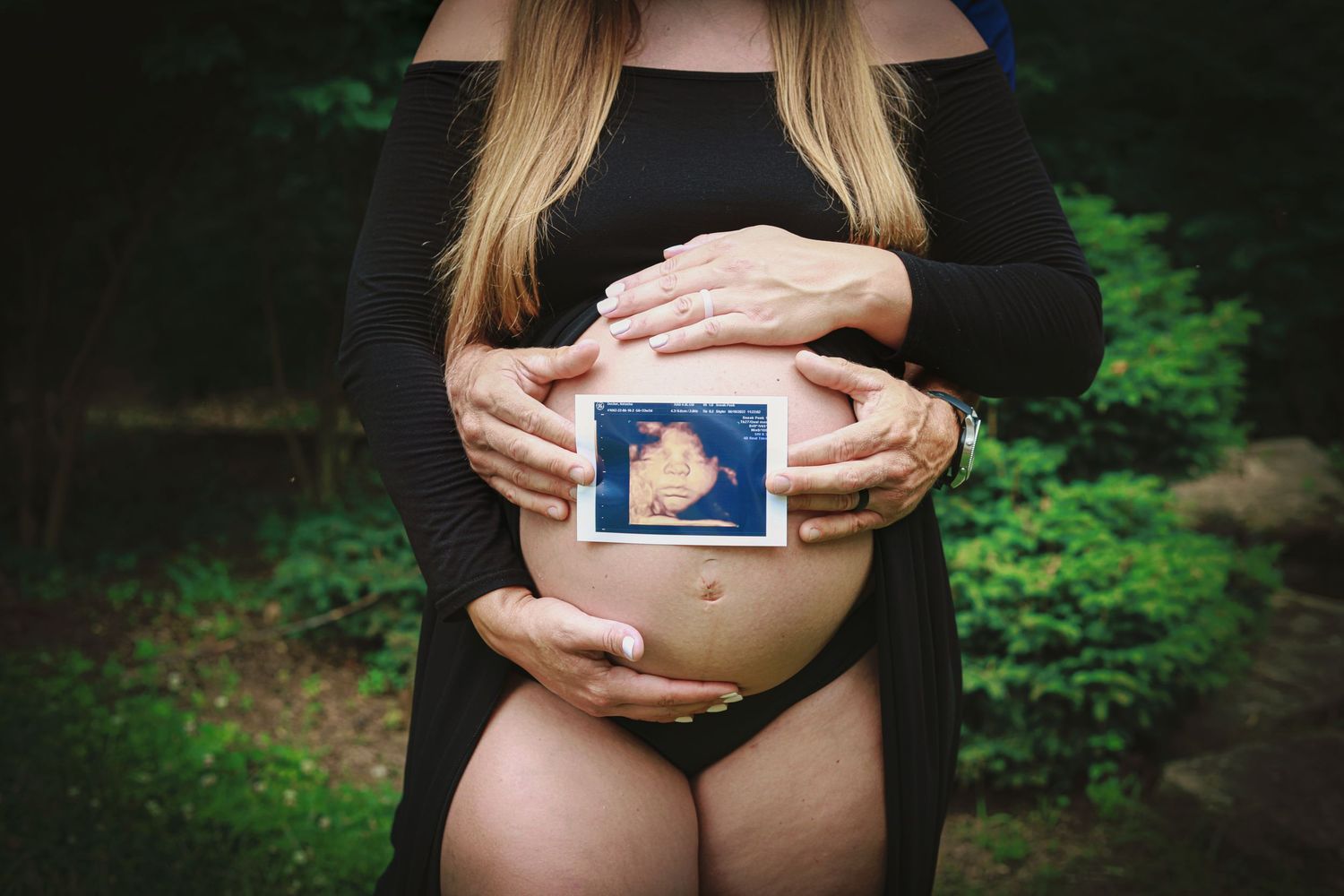 Maternity belly with mom and dad holding ultrasound.