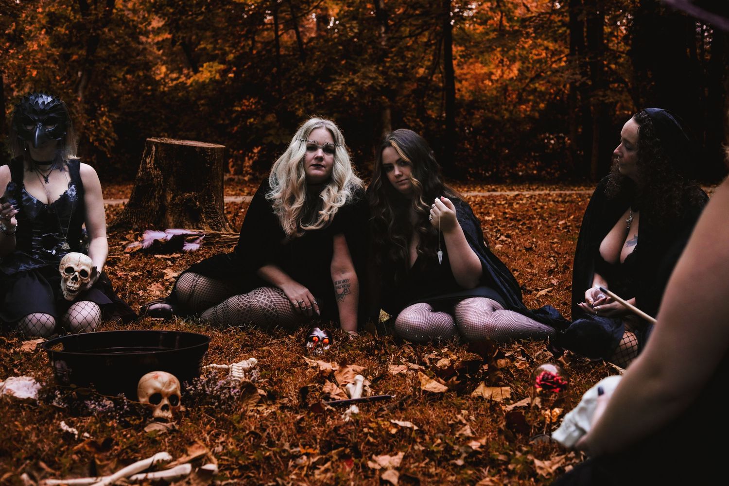 Mother and daughter wearing black lace and stockings sitting on ground in Greenwood, IN casting a spell out into the universe.