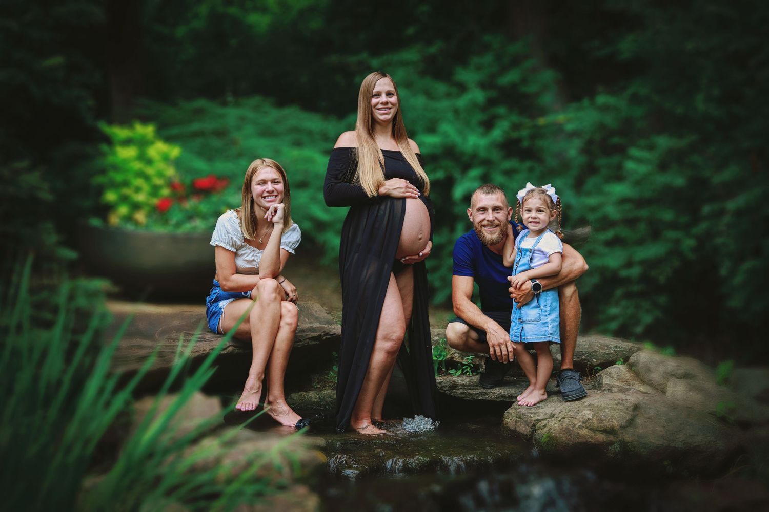 Pregnant mom, dad, and sisters on waterfall at Apple Works in Trafalgar, IN for maternity session.