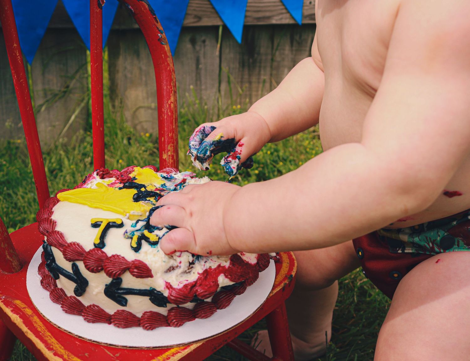 Birthday boy digging into smash cake outside in Greenfield, IN.